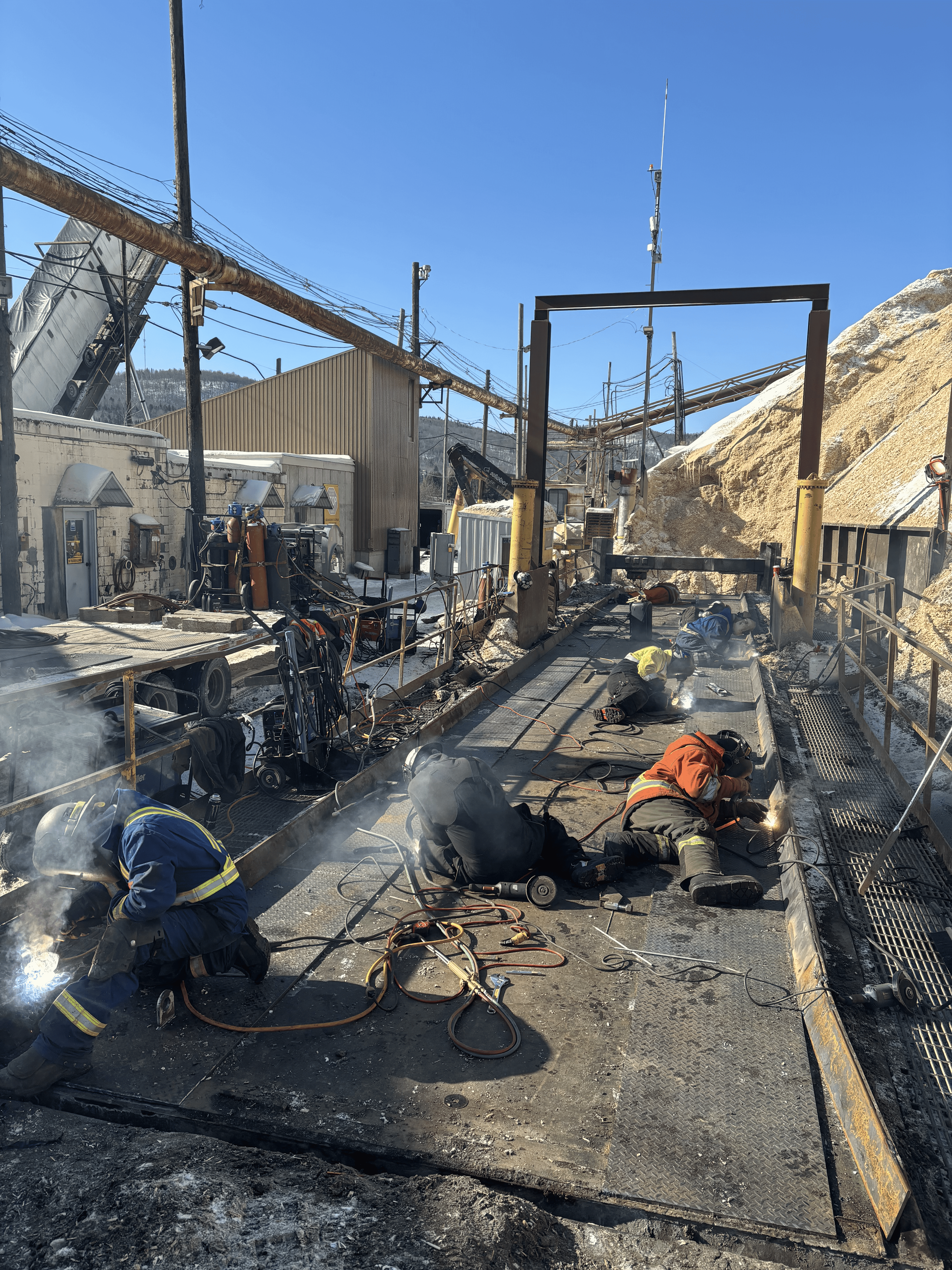 Group of people gathered around a wooden table with laptops, shaking hands during a team meeting.