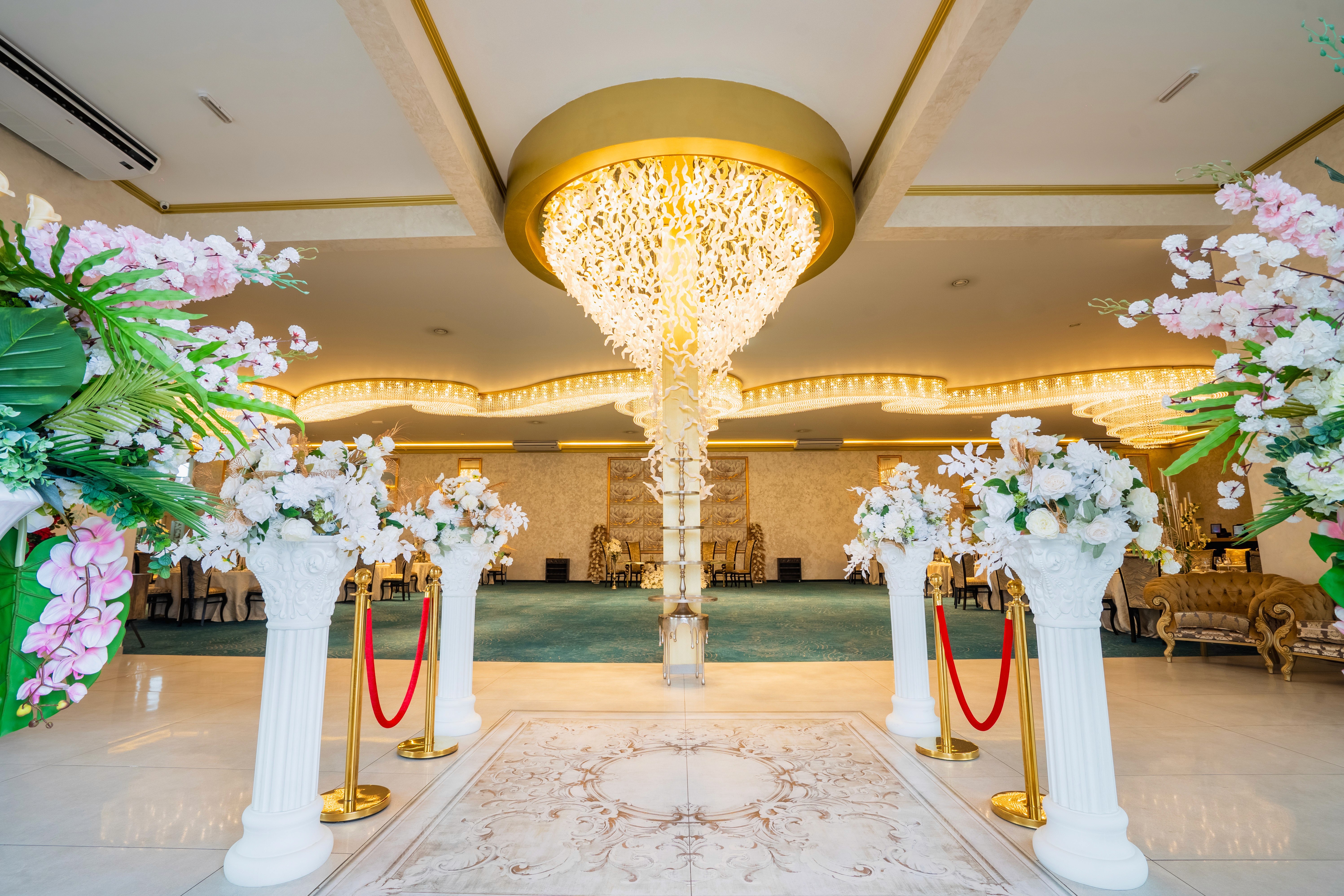 A serene outdoor seating area with two chairs, surrounded by lush greenery and a glassed-in structure.
