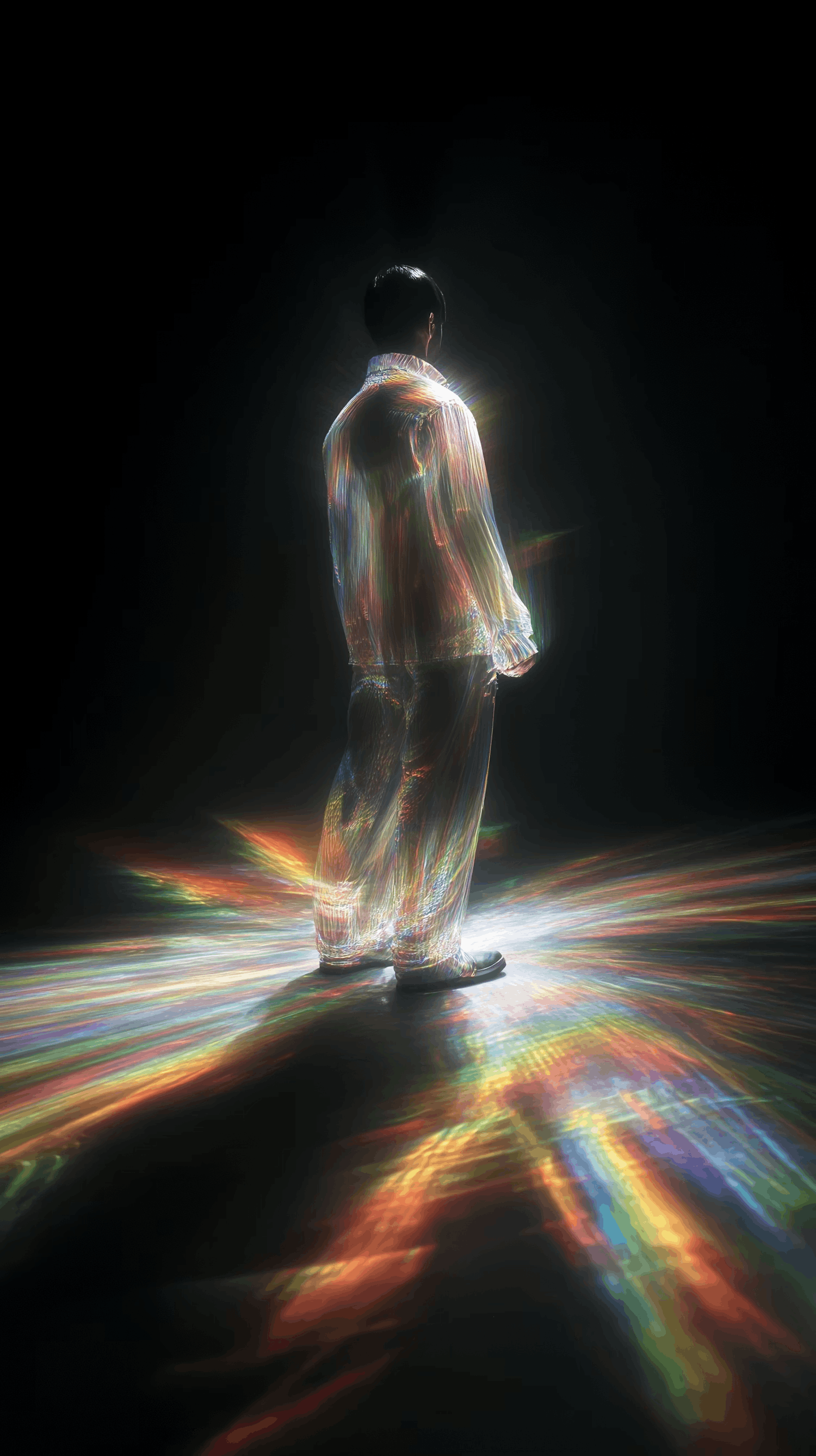 Person from back in glowing rainbow suit, standing on multicolored floor.