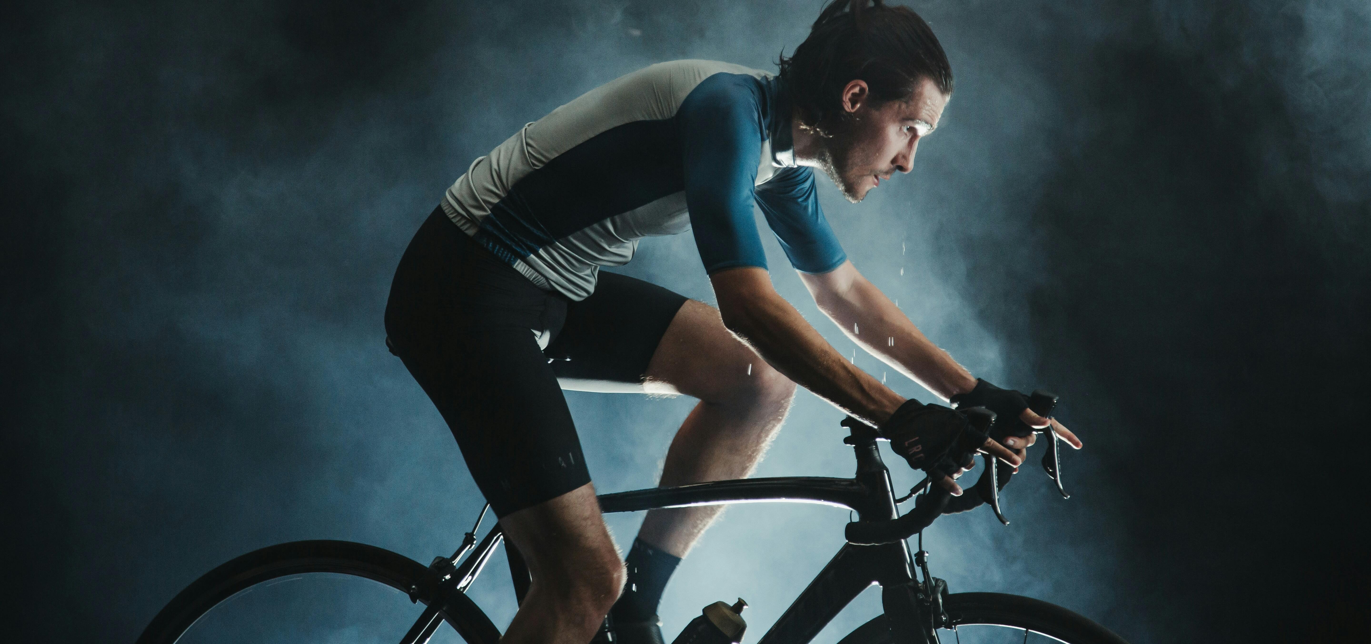 Cycliste sur route concentré en plein effort sous un éclairage dramatique, illustrant l'expertise technique et la passion de l'équipe BFZ Cycles.
