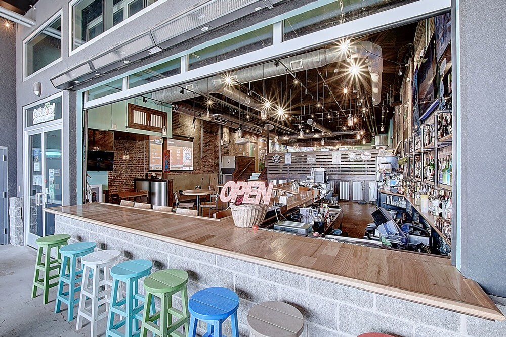 A view of a modern café with large windows, showcasing a cozy interior and seating outside.