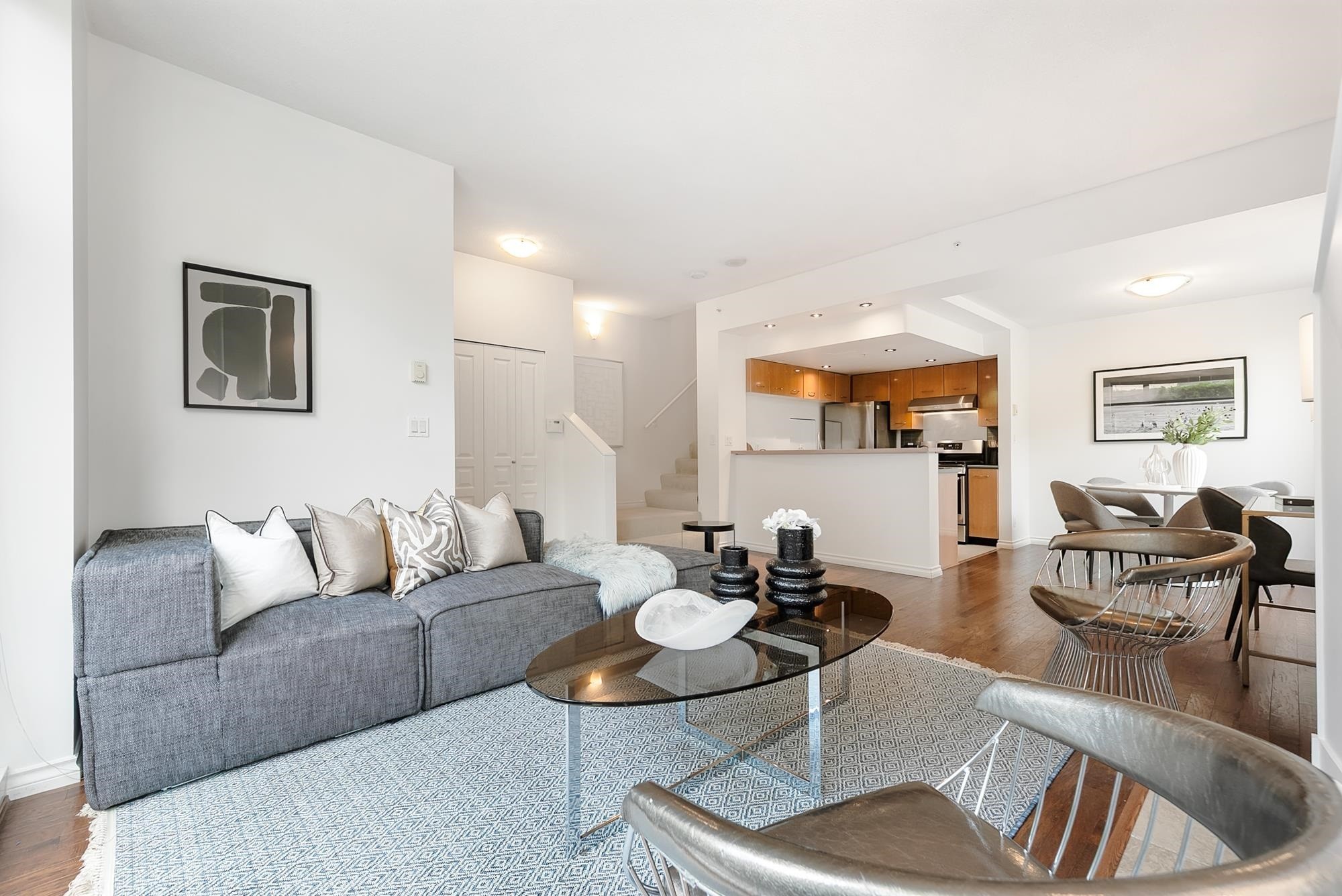 Modern living room featuring a gray sofa, coffee table, and open kitchen in a bright, airy space.