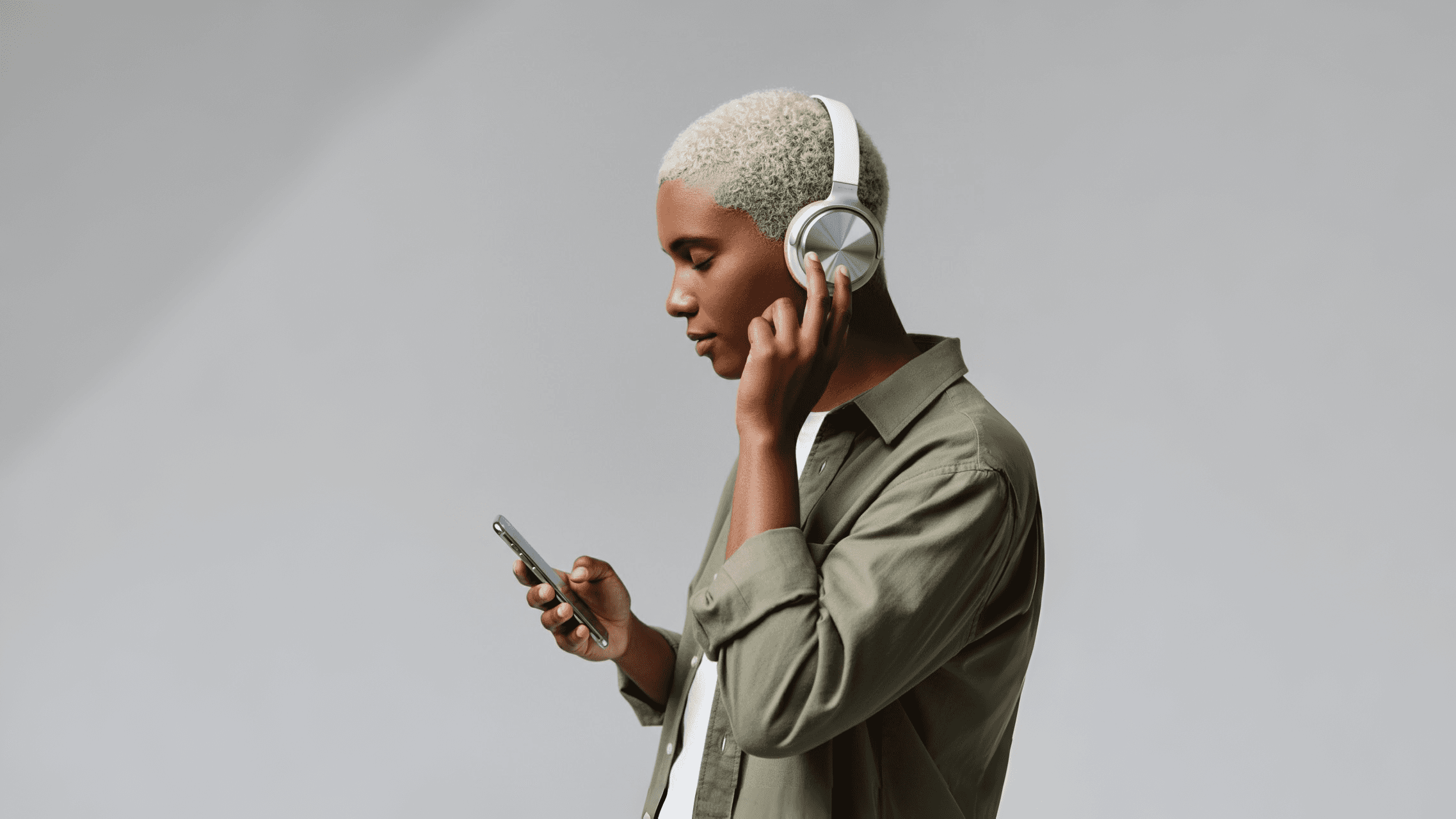 Man wearing silver headphones listening to music.