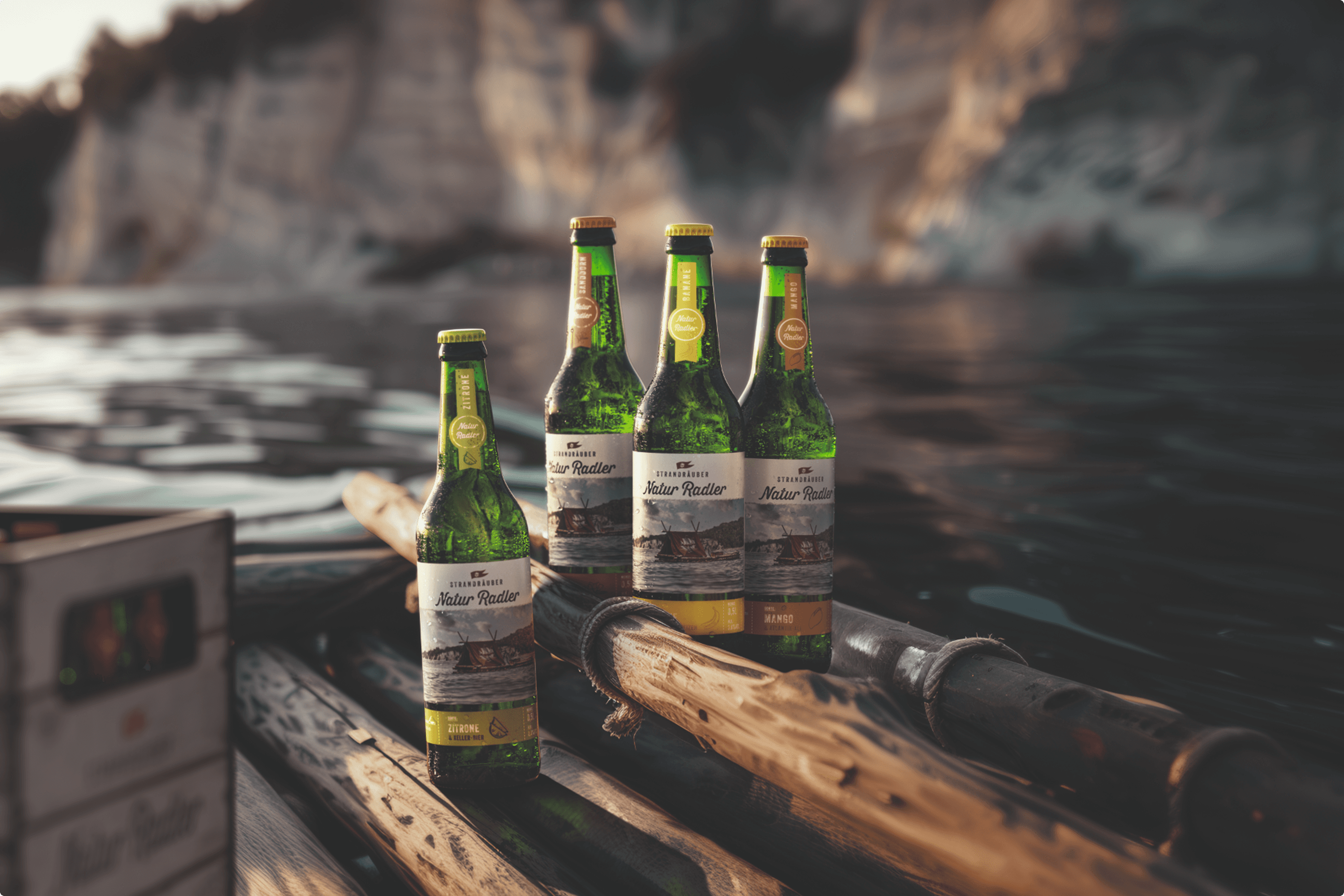 Four bottles of Natur Radler beer on logs near water.