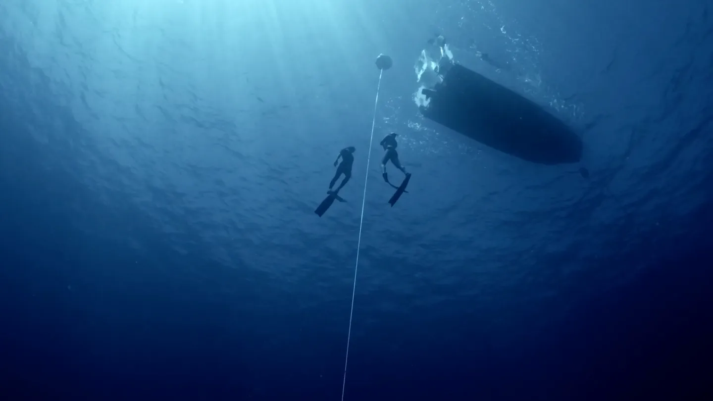 Two people freediving underwater