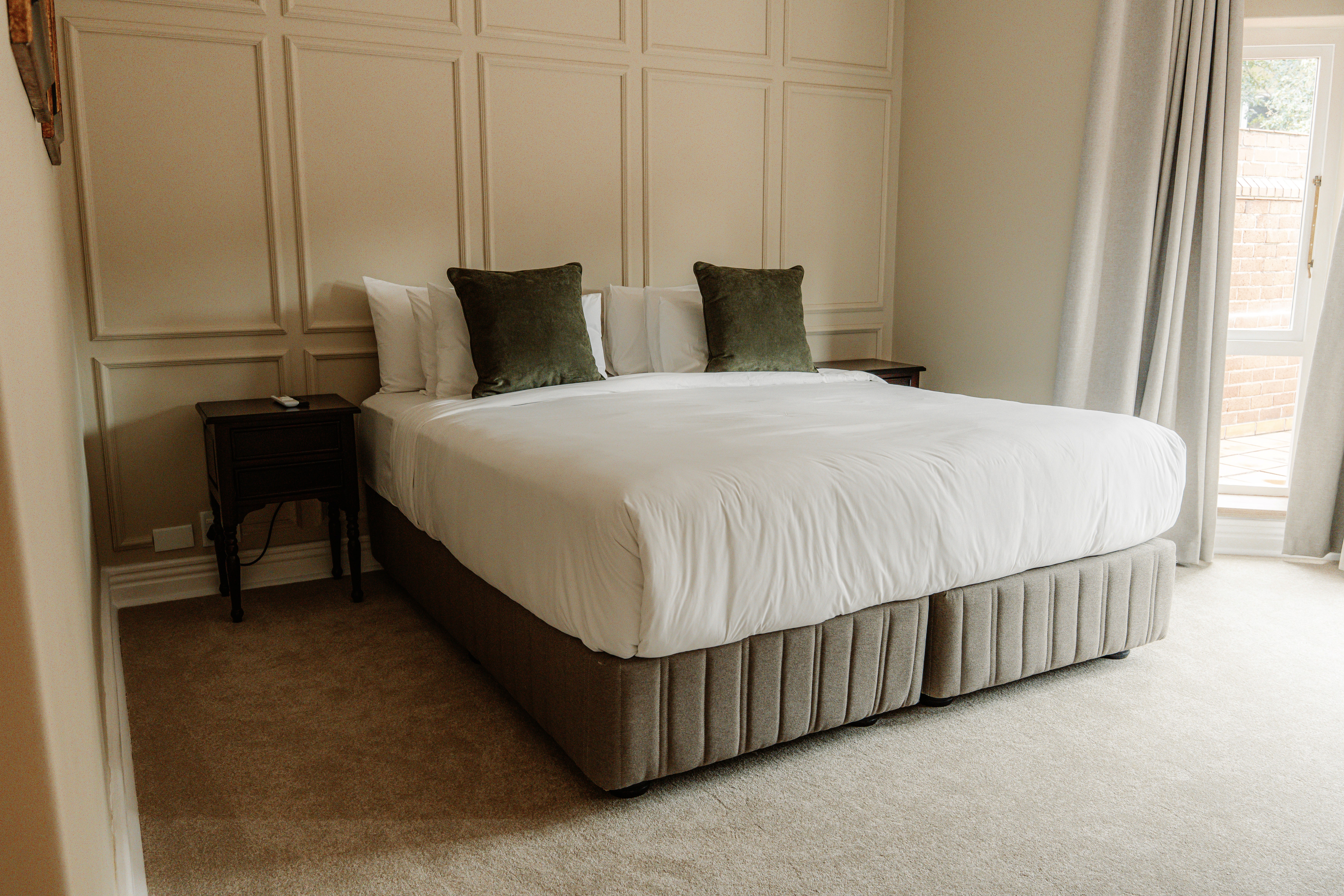 Redlands Hotel Deluxe Suite featuring a king-size bed, elegant furnishings, sitting area, and large windows with city views.