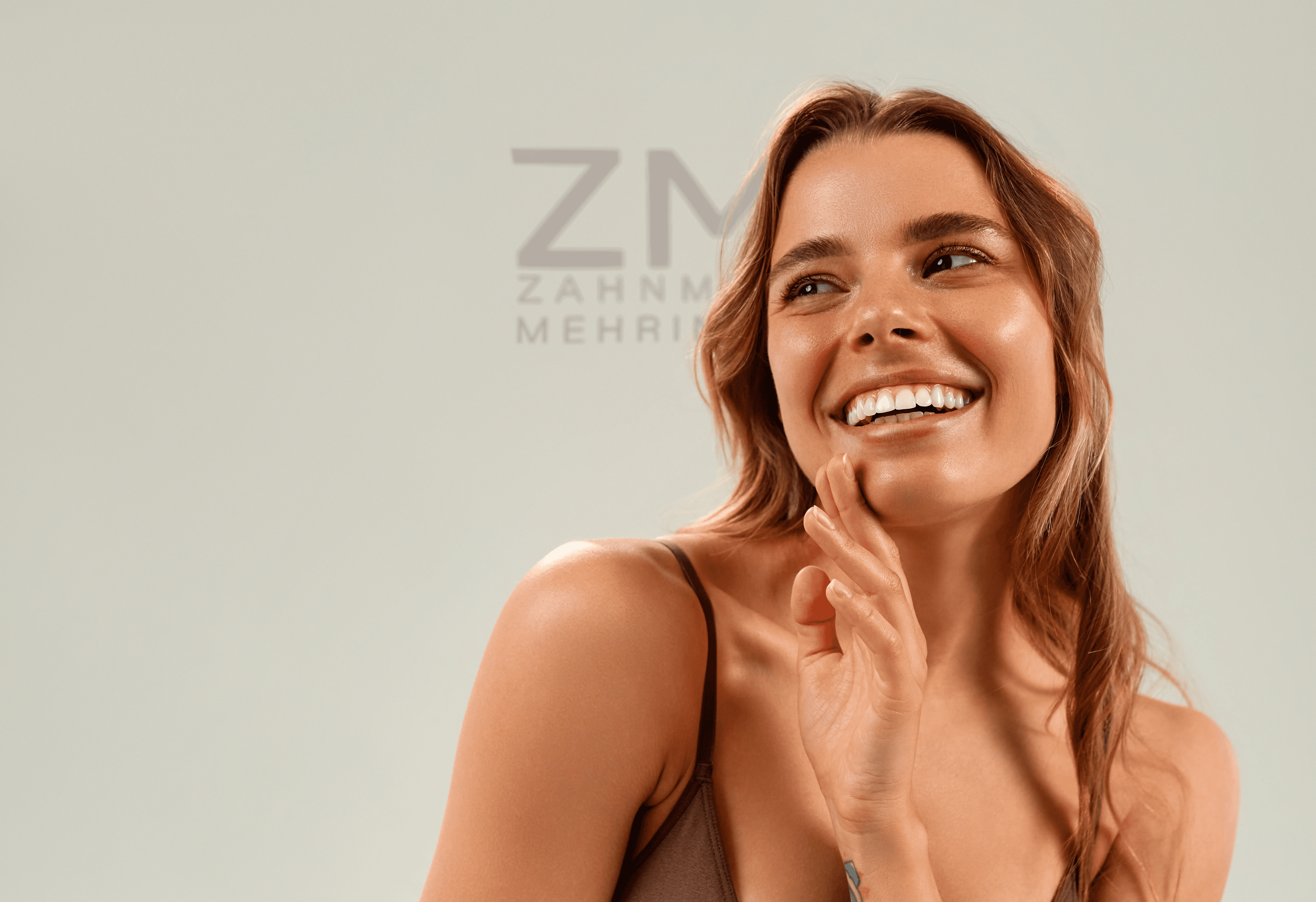 Close-up portrait of a woman with long red hair, closed eyes, and a soft expression, against a beige background