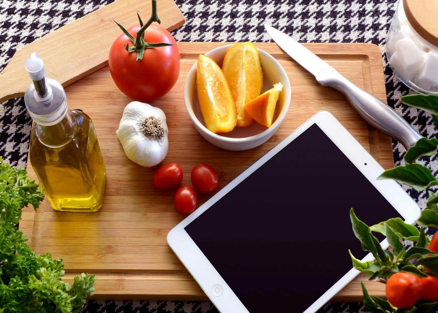 White iPad on cutting board with olivie oil and fruits and veggies