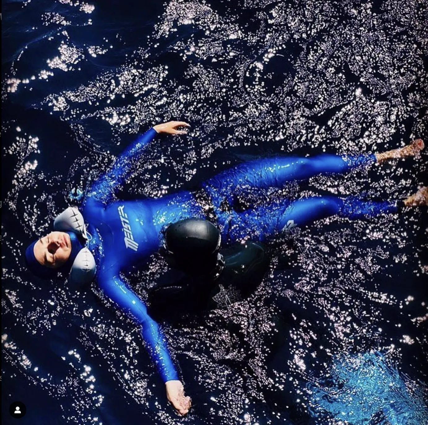 freediver meister lying on water with another freediverhelping