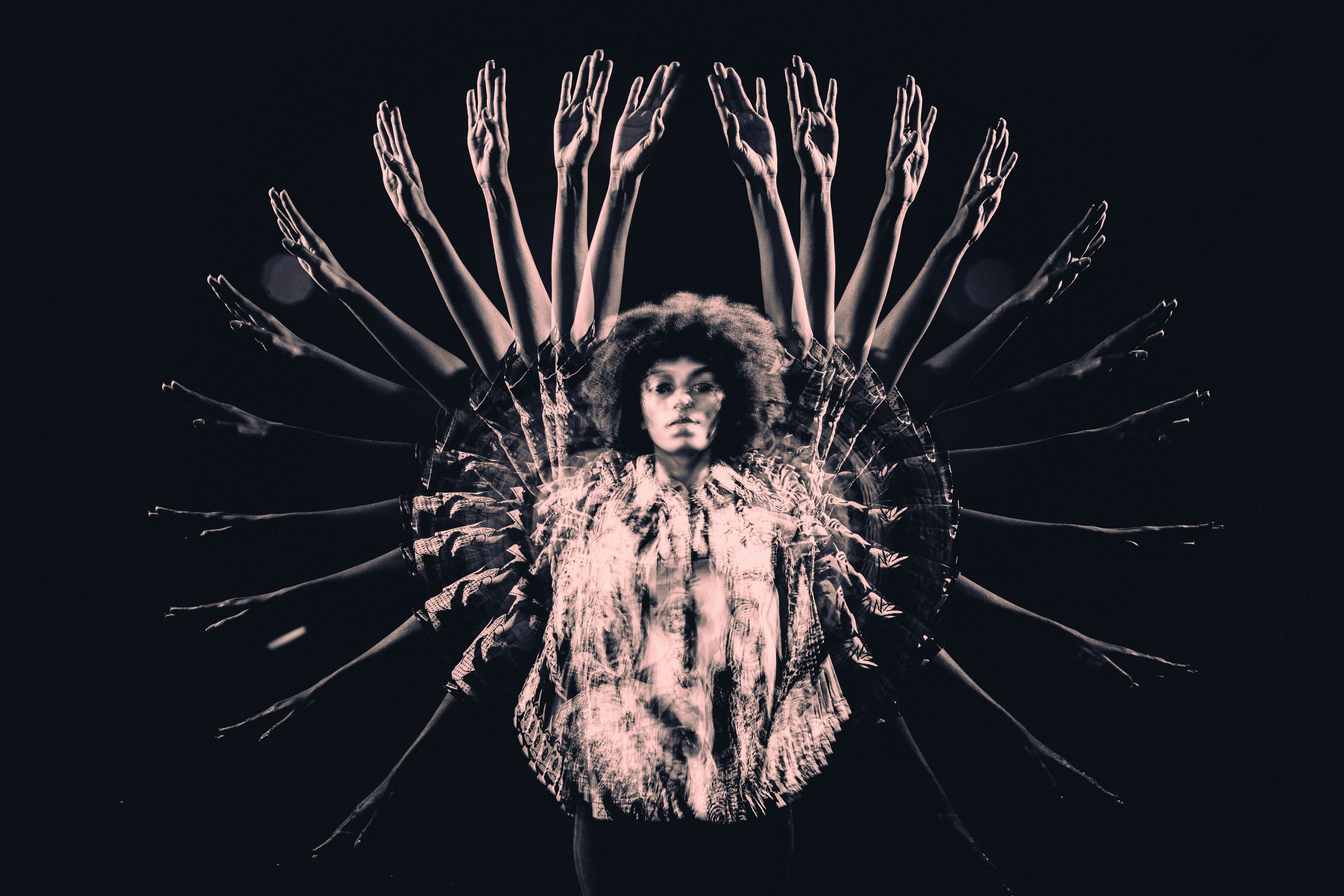 Überlagerte Silhouette einer Person mit vielfach ausgebreiteten Armen vor dunklem Hintergrund – visuelle Metapher für Teamarbeit, Vielfalt und gemeinsame Ausrichtung.