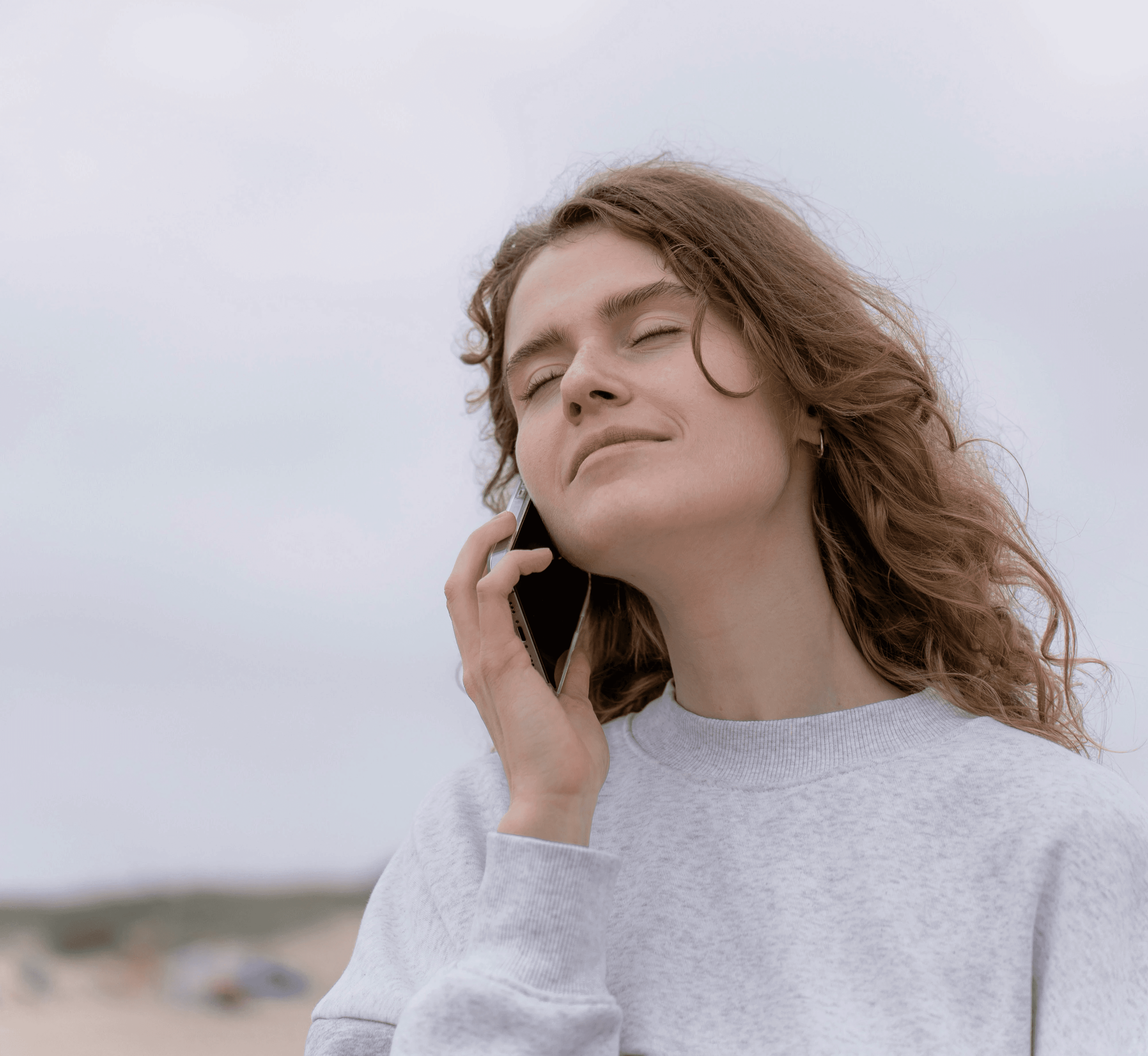 a woman standing on the beach talking on a cell phone