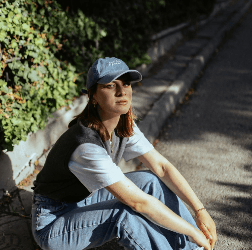 Person sitting outdoors wearing cap