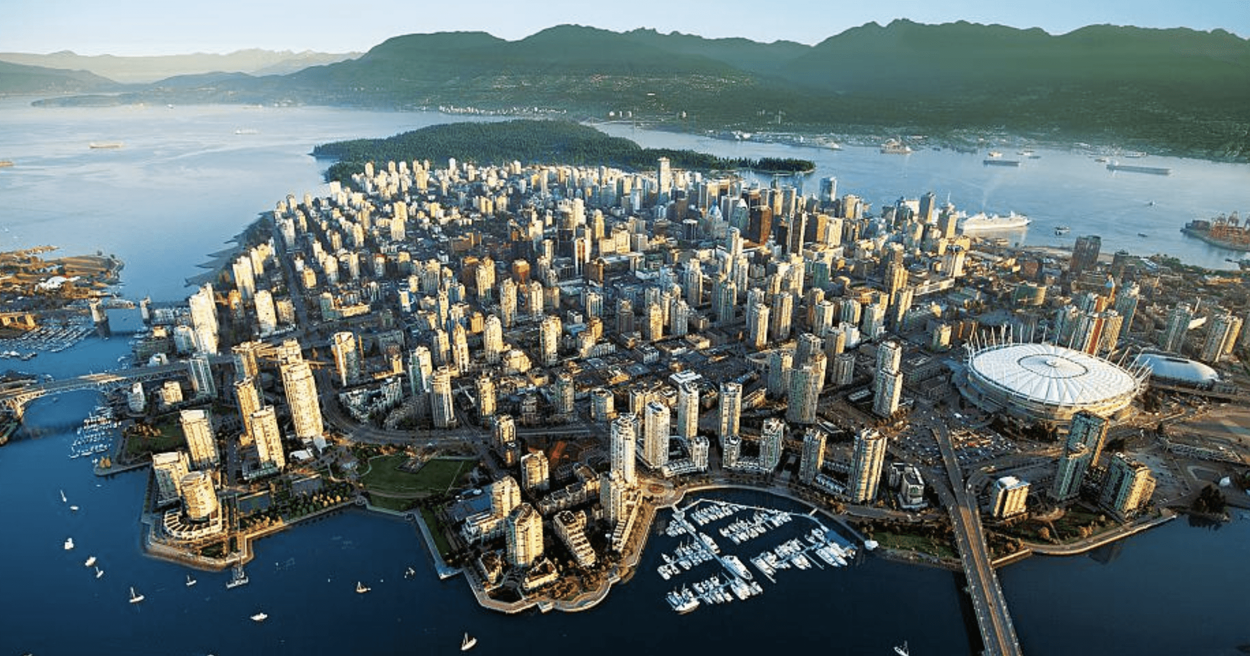 Real estate SEO services Vancouver help luxury properties like this waterfront hotel stand out online. Aerial view of Vancouver downtown skyline with North Shore mountains, luxury high-rise condos along False Creek, blue hour lighting, real estate development perspective, clean modern cityscape