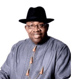 Close-up portrait of a freckled woman with soft pink hair and star earring, natural light, white tank top.