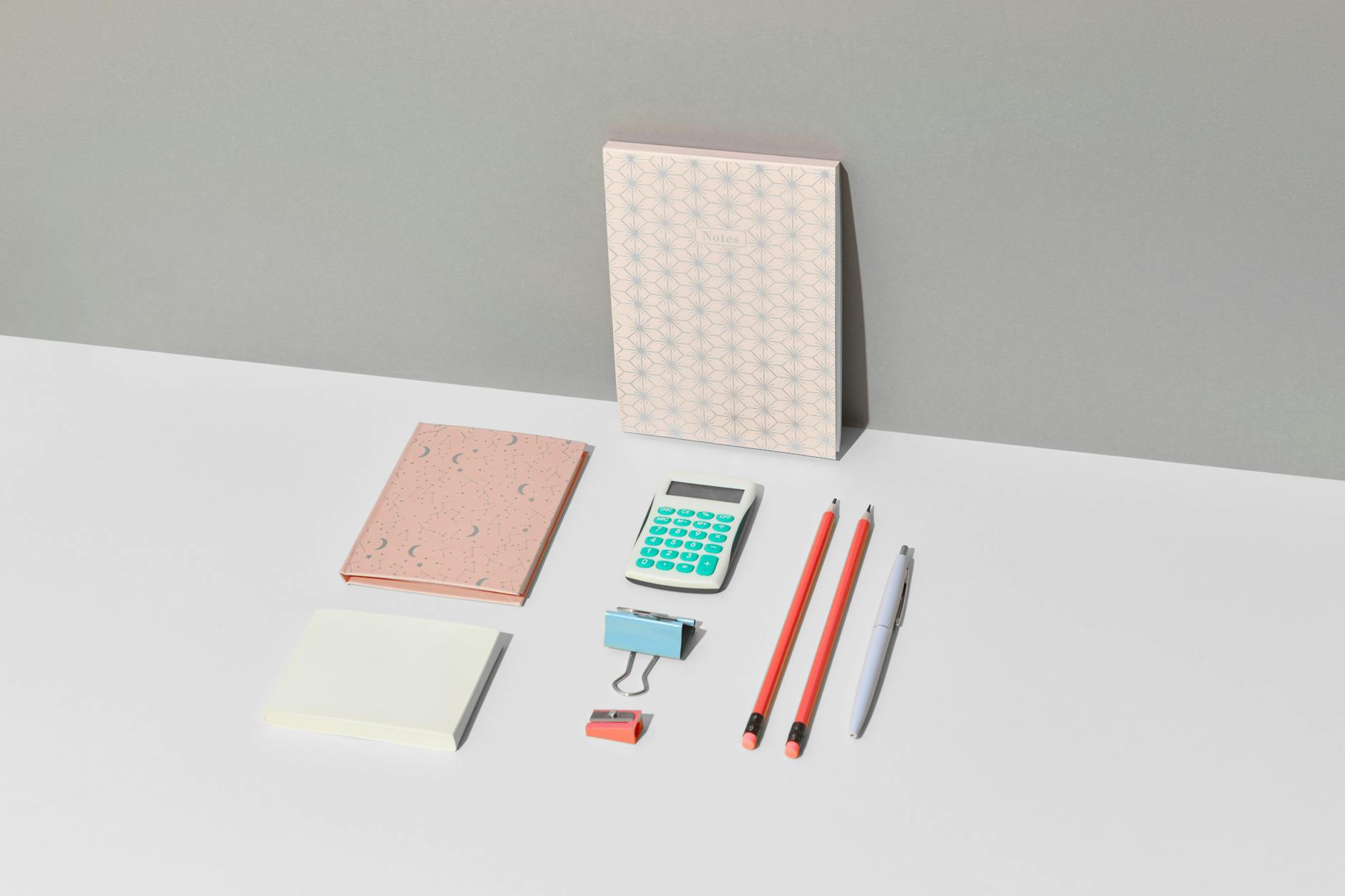 Close-up of a wooden desk featuring an open notebook with geometry sketches and a colorful calculator.