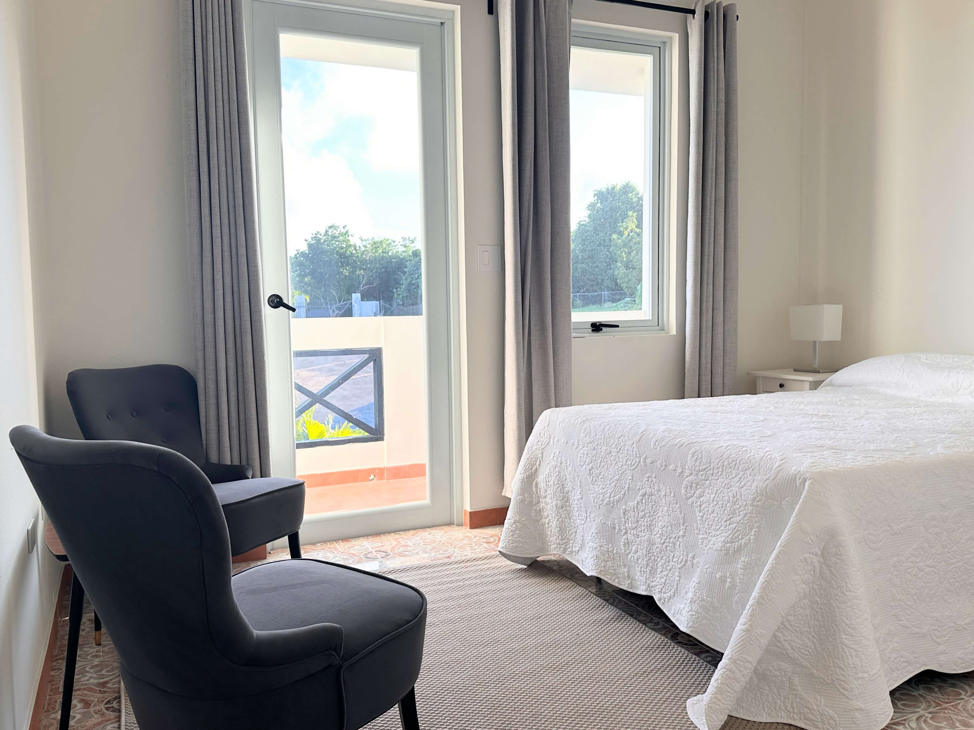 Interior of Club Vieques Room 11 featuring a queen bed, modern furniture, and a balcony with a tropical view.