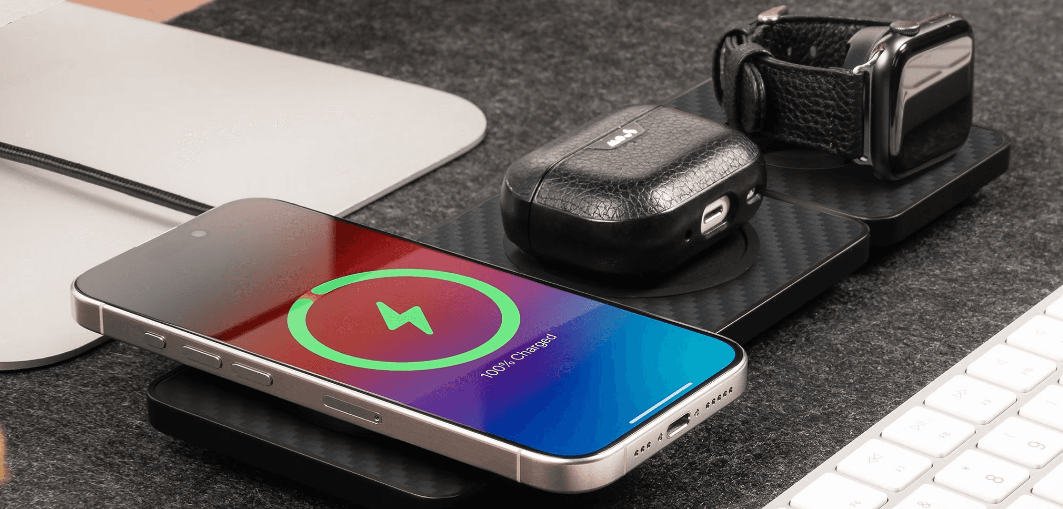 Wireless charging station powering a smartphone, earbuds, and smartwatch on a desk setup.