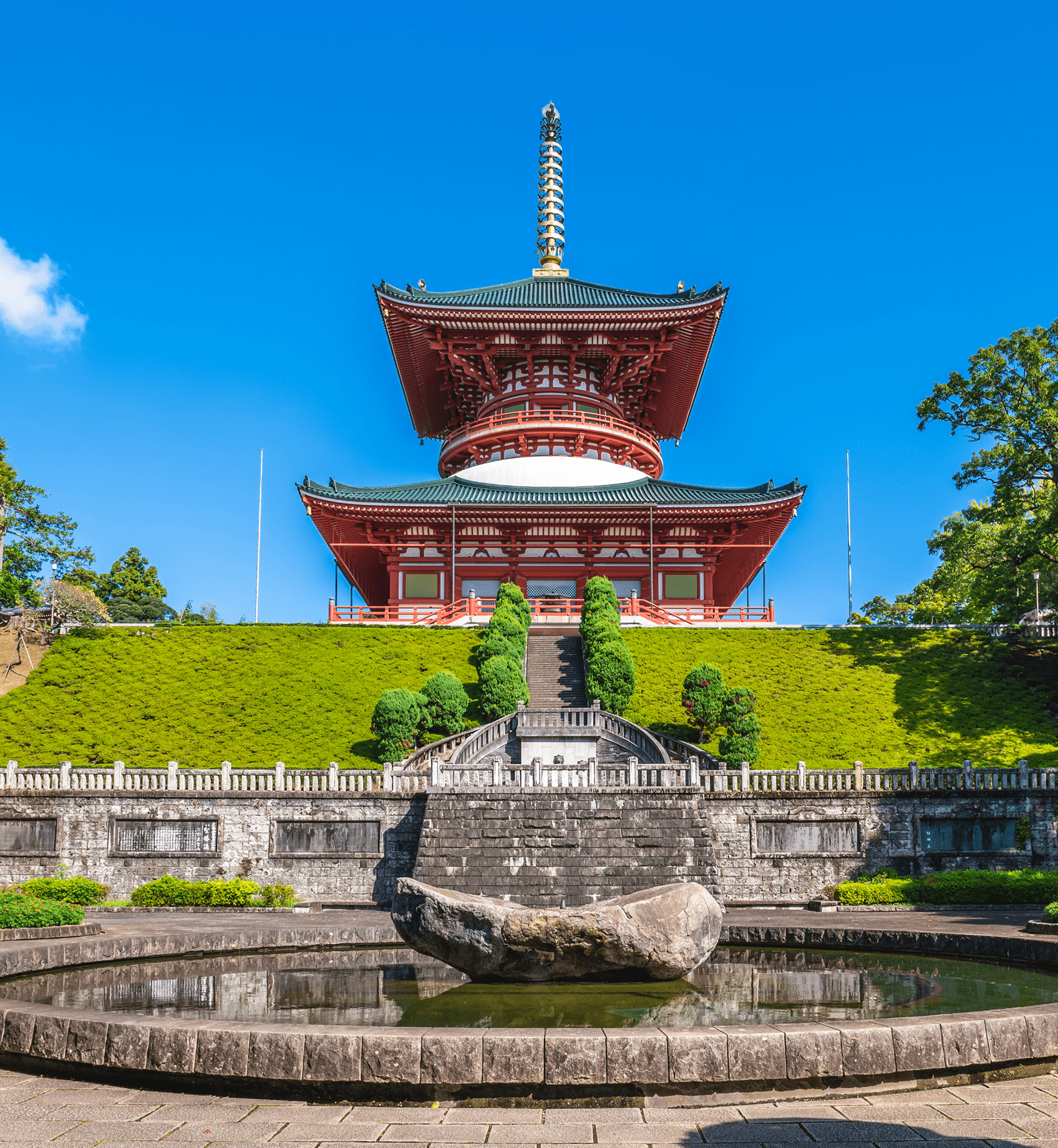 Colorful Japanese pagoda on a green hillside under a clear blue sky.
