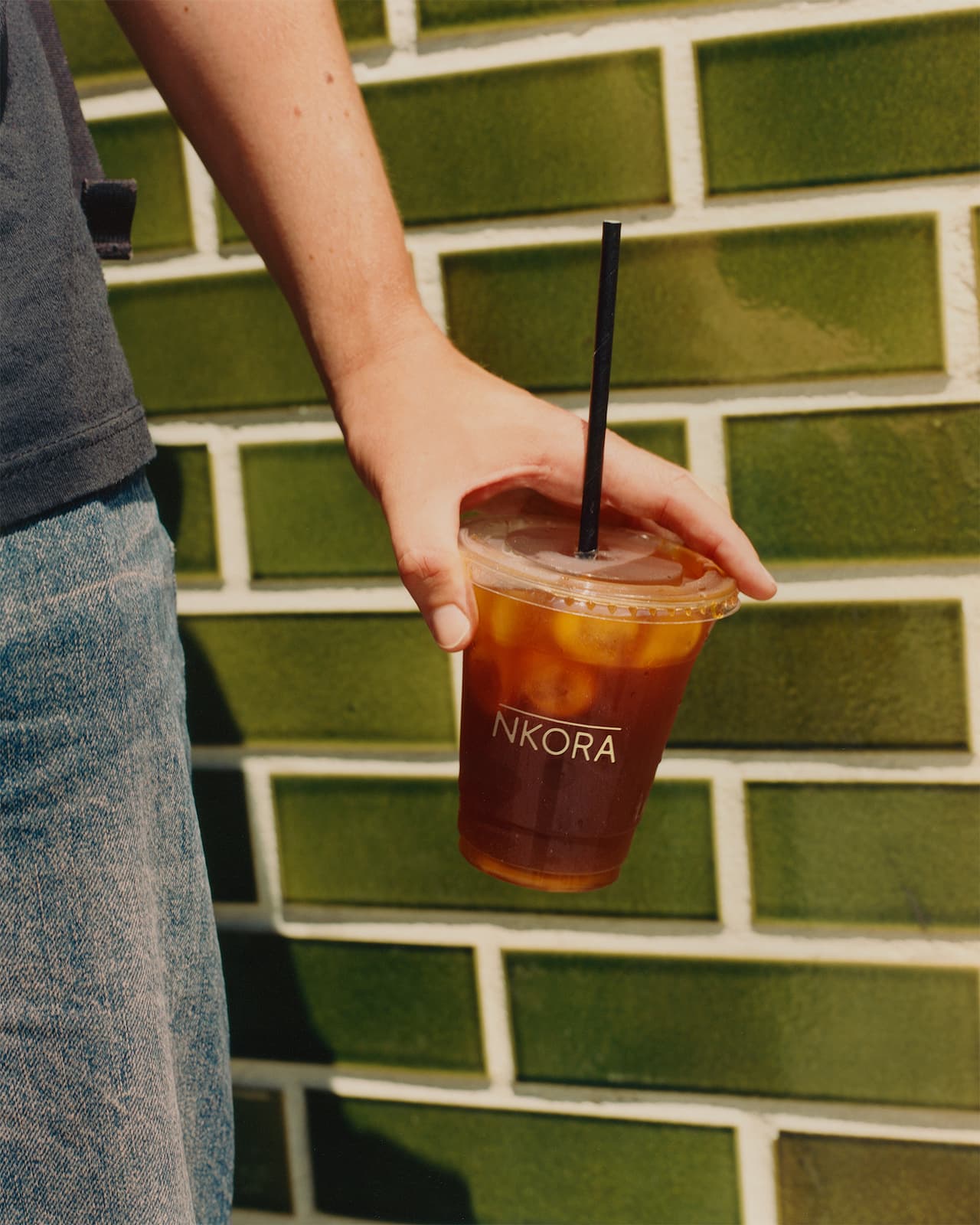 Person holding a NKORA coffee cup