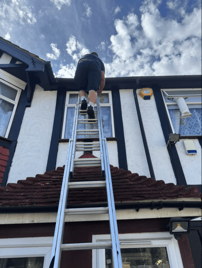 Roofers removing old tiles and timber battens from a pitched residential roof during renovation.
