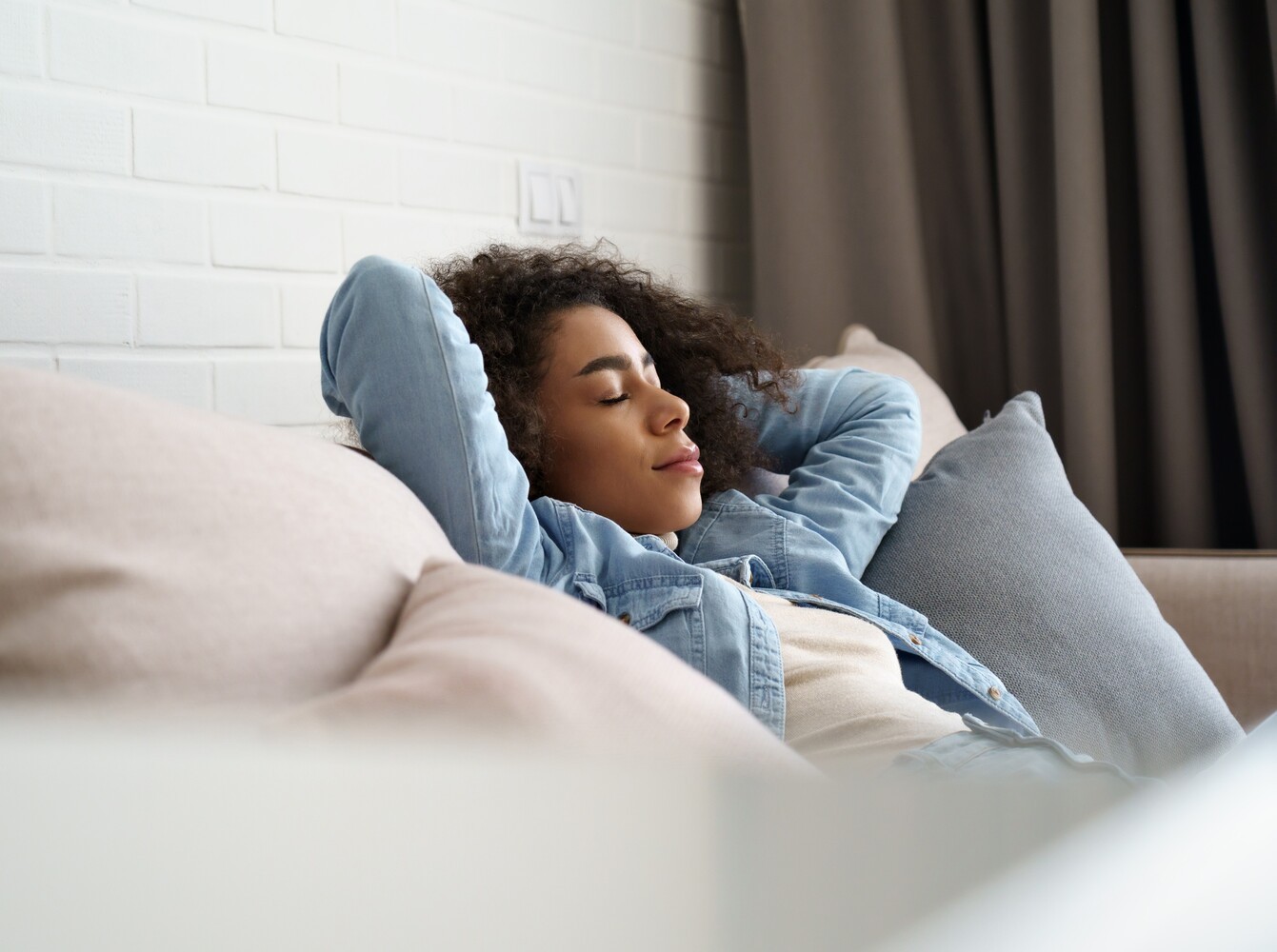 woman taking time to rest on the couch with her eyes closed after doing the best treadmill workout to lose weight