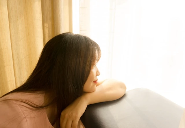Woman looking out of a window in soft morning light