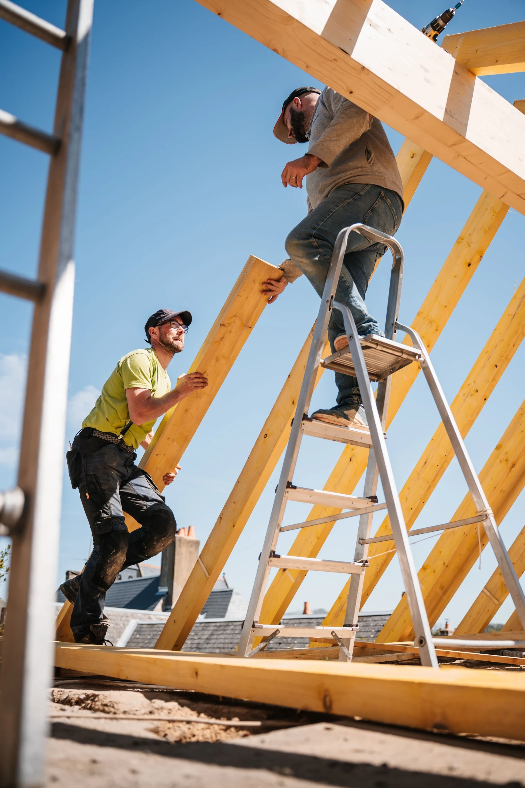 Roofer climbing a ladder beside a roof frame