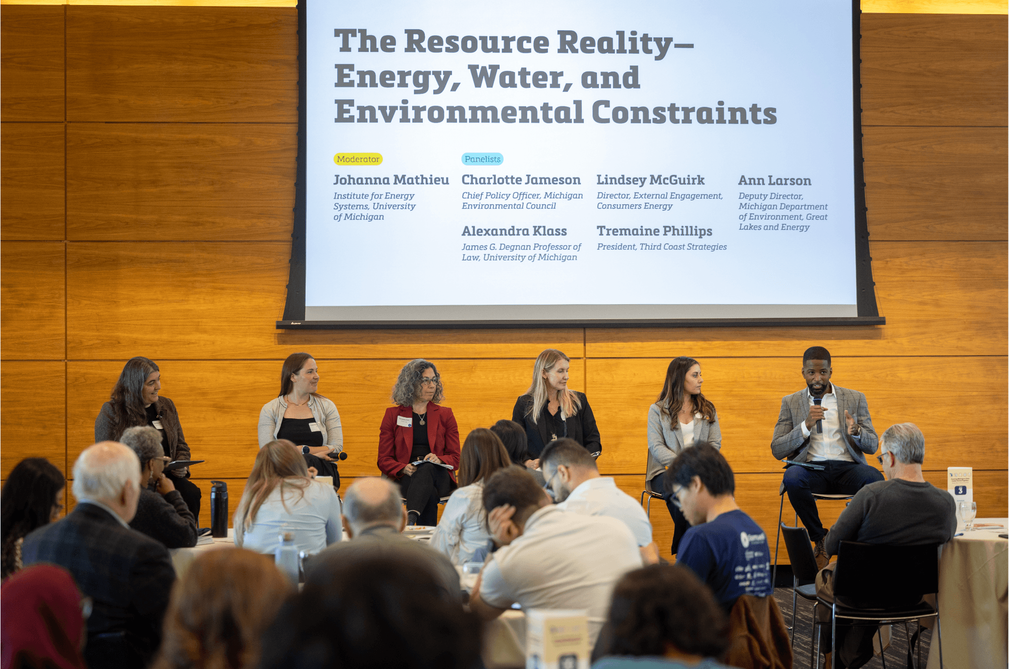 People on stage talk on a panel. Behind them a screen says: the  resource reality - energy water and environmental constraints
