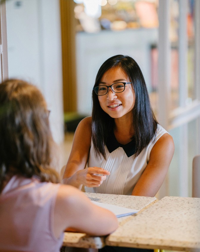 Two women sitting vertically opposite one another and having a conversation.