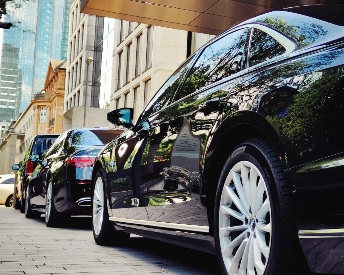 Audi A8 Lang und weitere Limousinen in der Hoteleinfahrt vor der Frankfurter Skyline