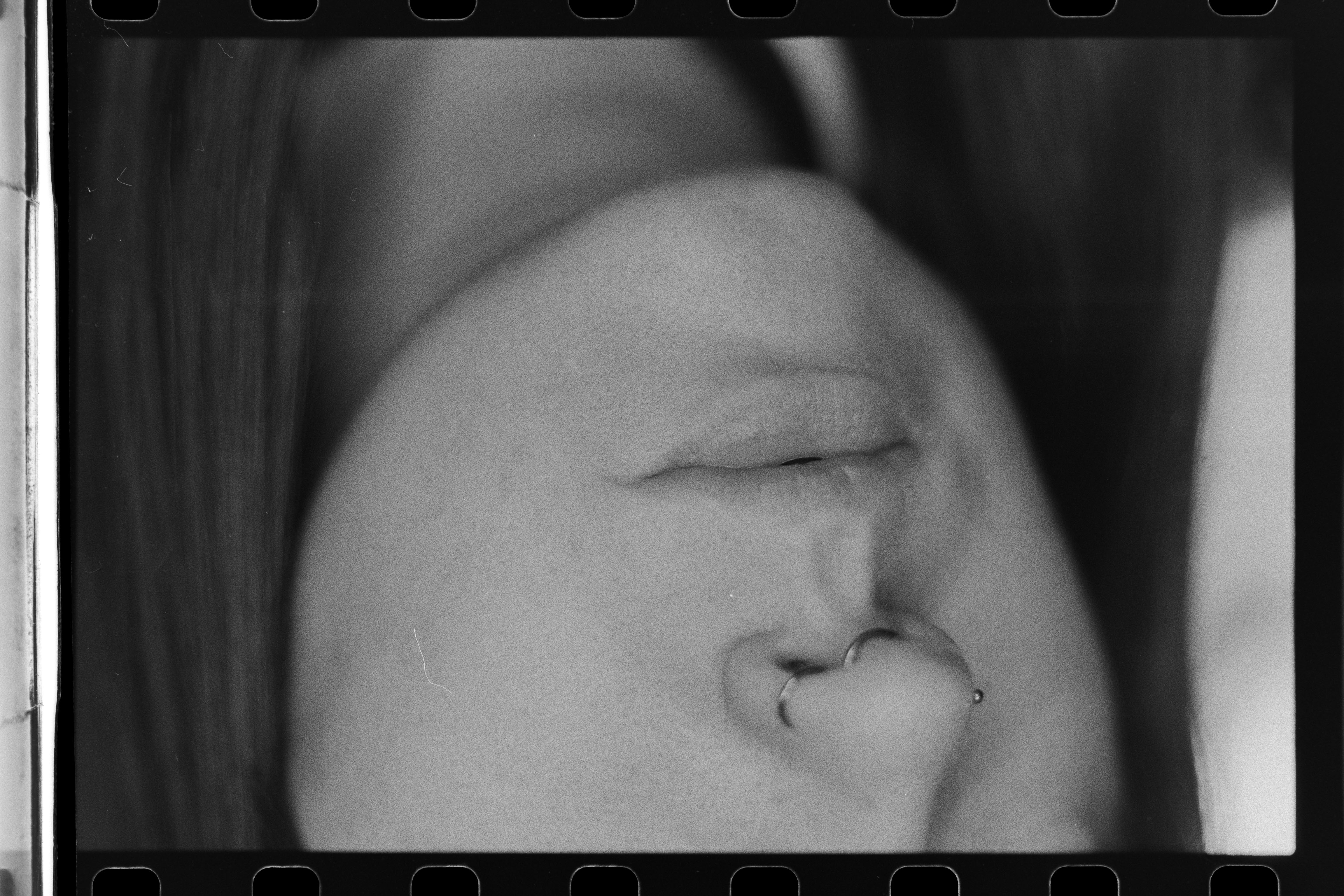 A close-up of a person wearing green-tinted glasses, with a serious expression and smooth skin.