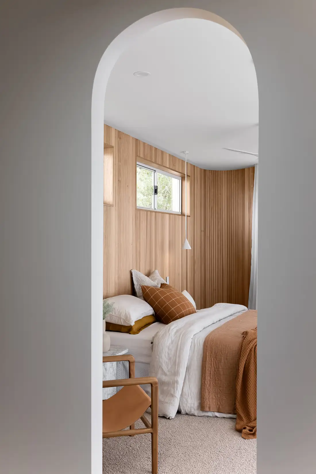 A bedroom with a bed visible through and arched doorway