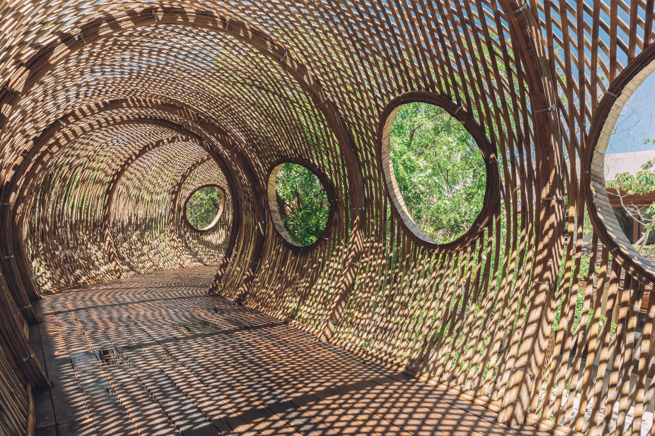 Inside view of the Cervecería Tulum structure, highlighting the circular apertures designed to frame the jungle views and allow natural airflow through the bamboo tunnel.