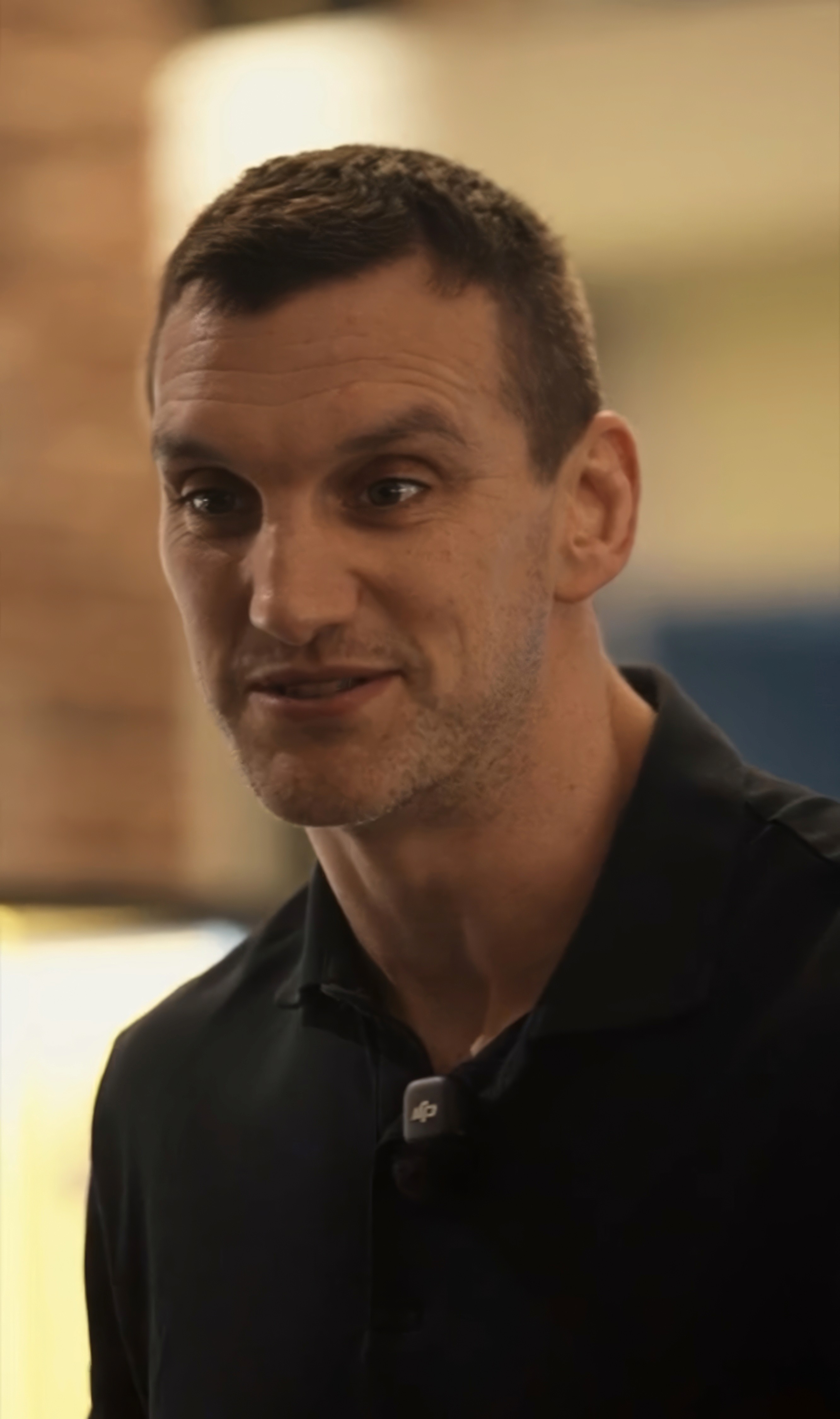 Bride sitting on ground against wall, groom standing nearby