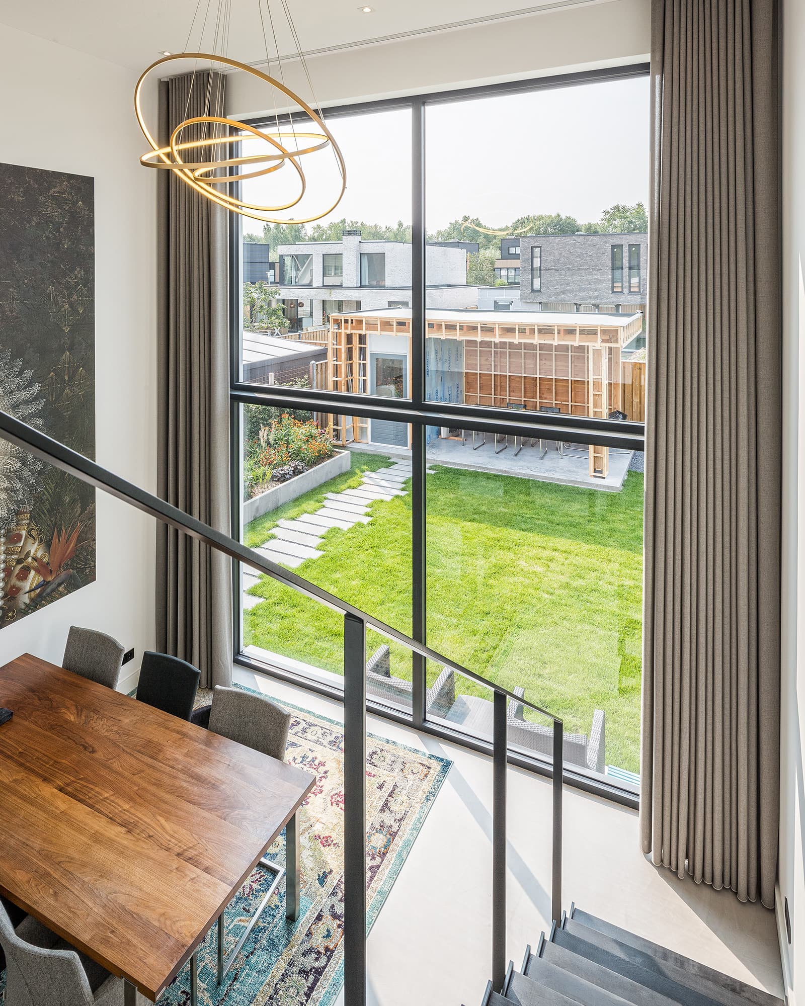 Eethoek bij grote glasgevel met uitzicht op de tuin en moderne ringlamp boven tafel