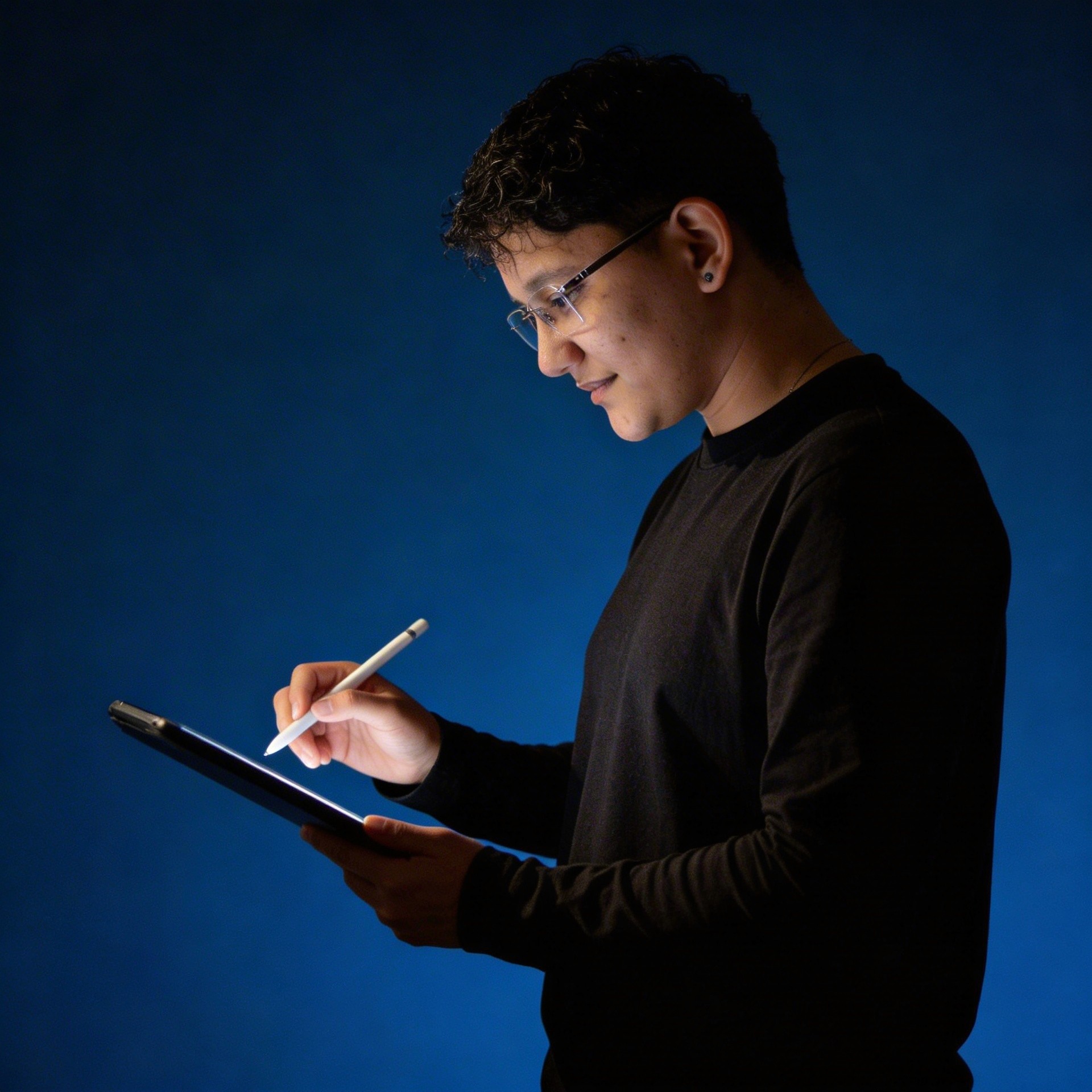 A thoughtful young person with dark hair gazes to the side, captured in soft black and white lighting.