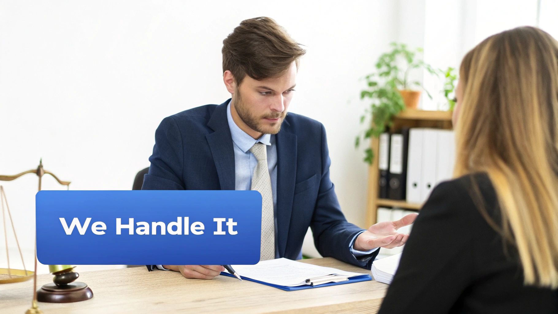 A male lawyer in a blue suit explains documents to a female client in an office, with scales of justice visible.