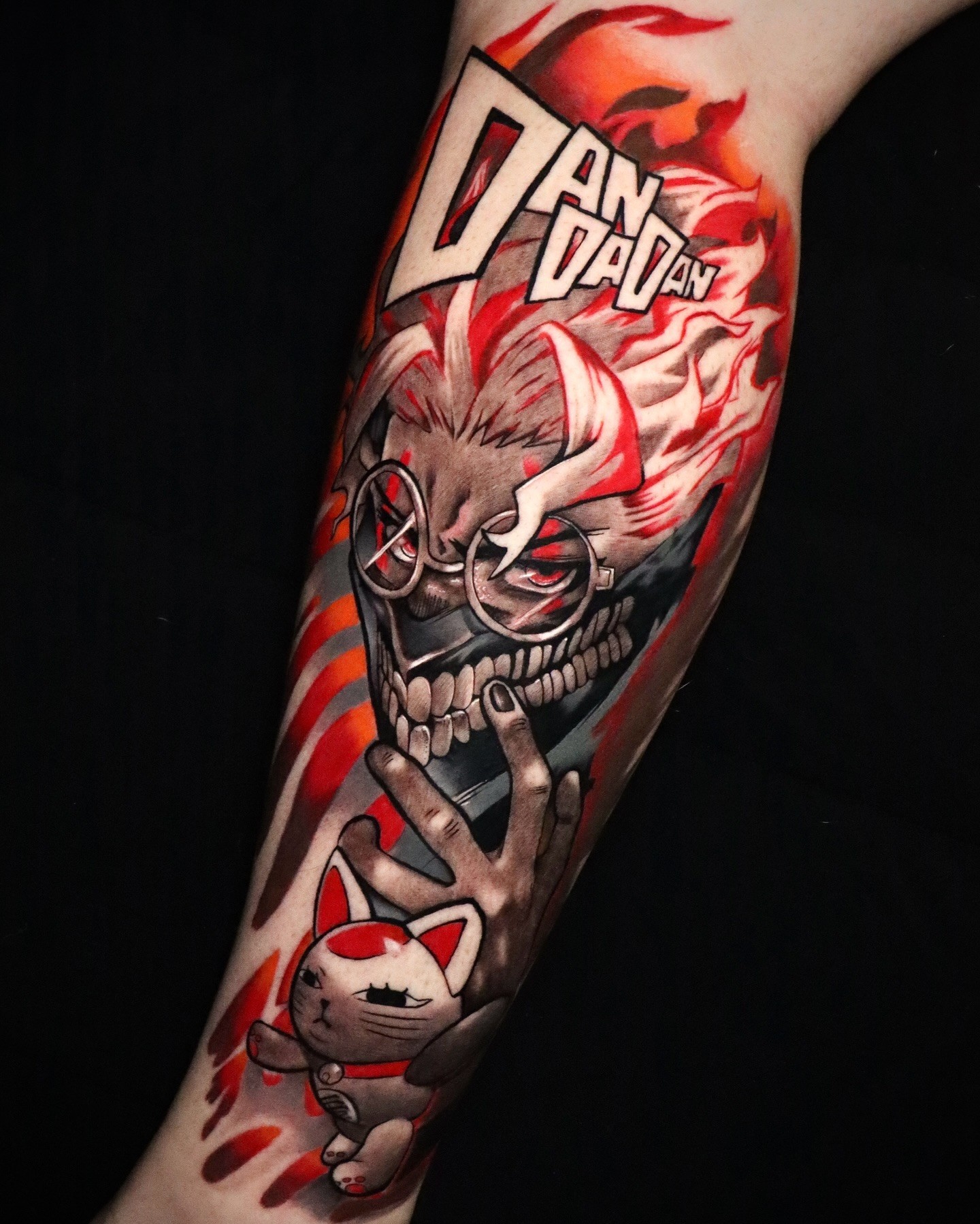 This bold tattoo showcases Okarun and Turbo Granny in a fiery explosion of color and intensity. The red flames surrounding the characters highlight the chaotic energy of the scene, with Turbo Granny's mischievous smirk and Okarun's defiant stance making for a visually dynamic piece. The inclusion of the "Dandadan" logo ties everything together, making this tattoo a vivid tribute to the anime's frenetic storytelling. Created by rareboyz_.