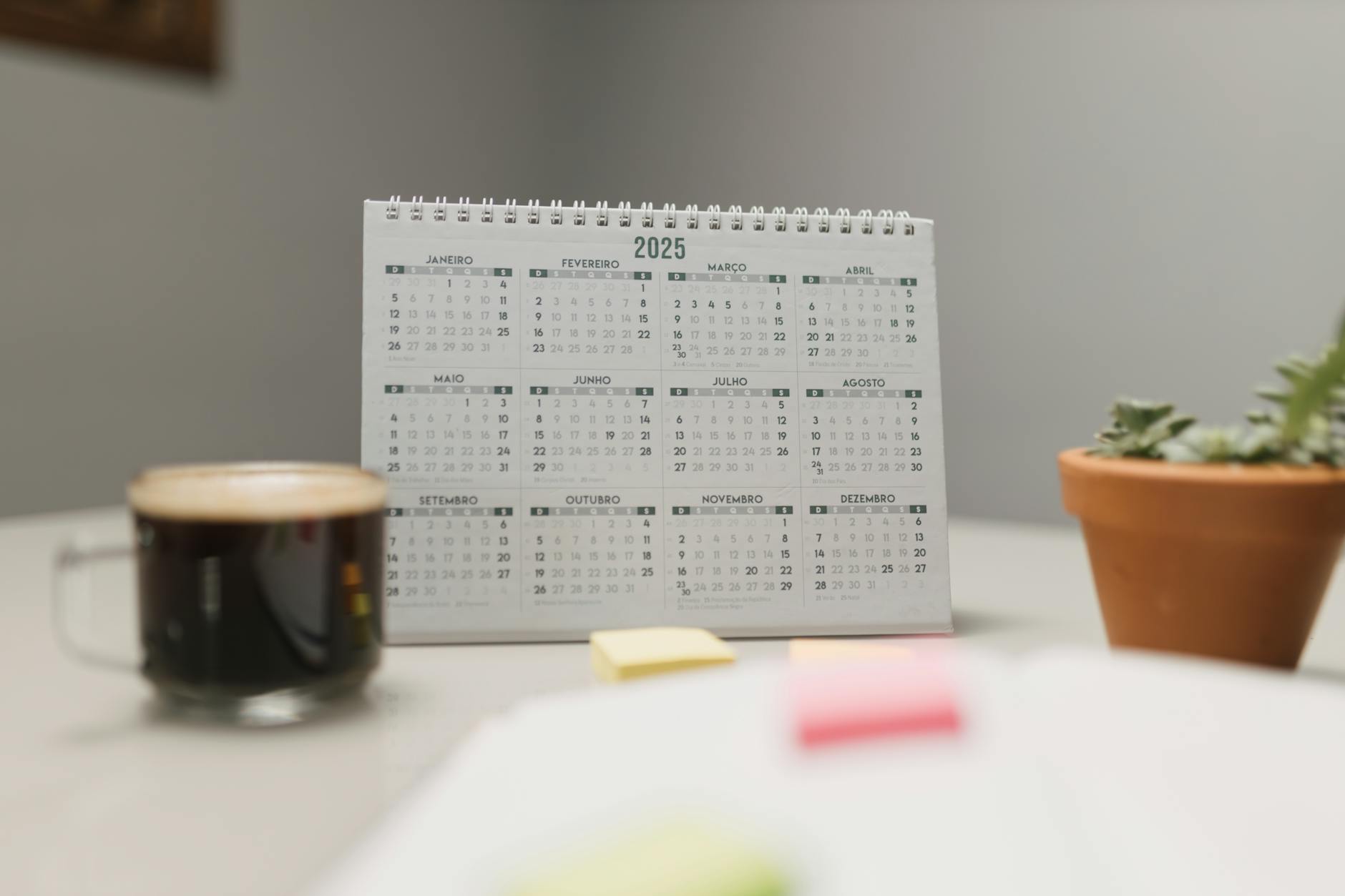 A hand marking a wall calendar with colorful stickers to track a monthly plan for diversity in the classroom.