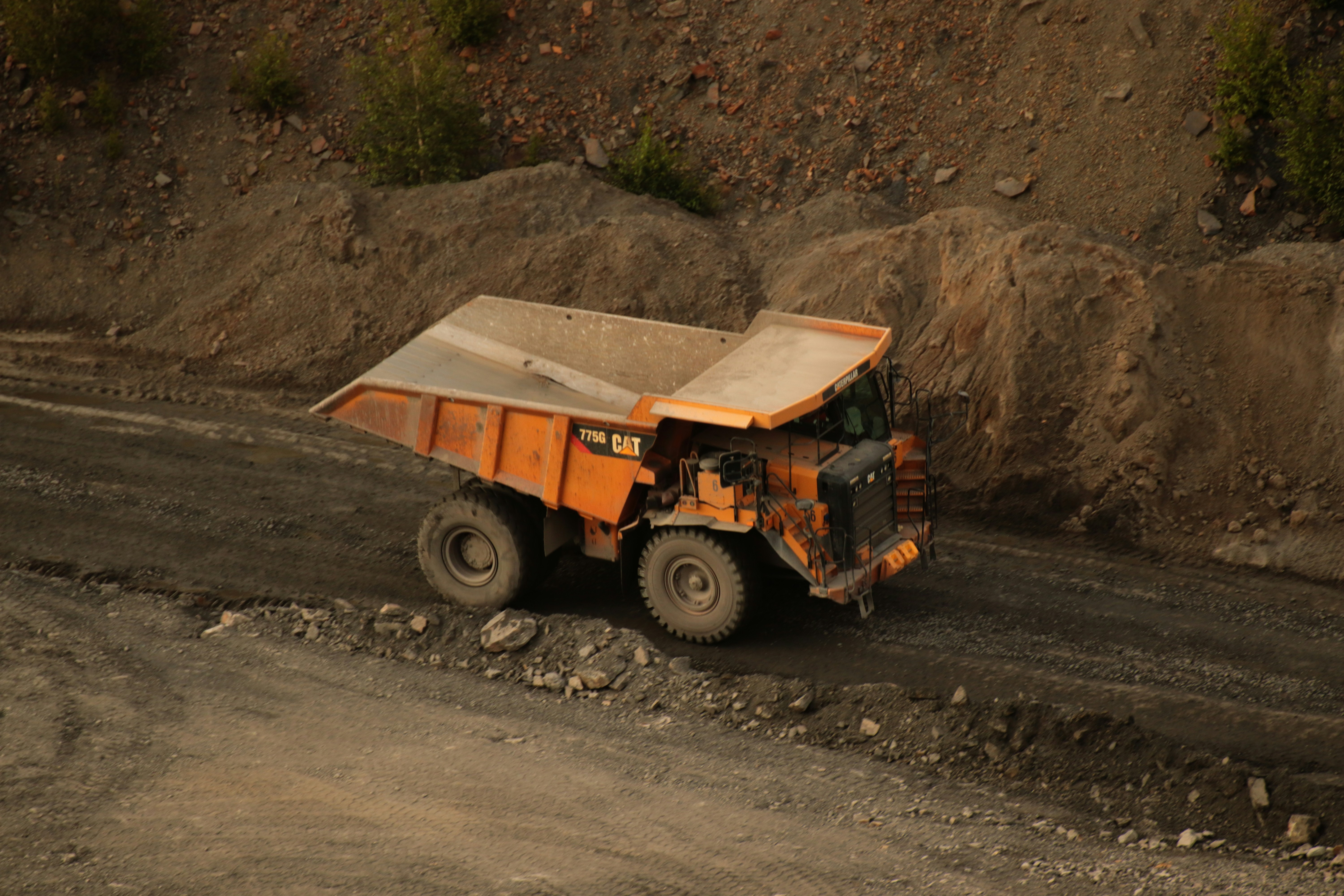 an orange dump truck driving down a dirt road