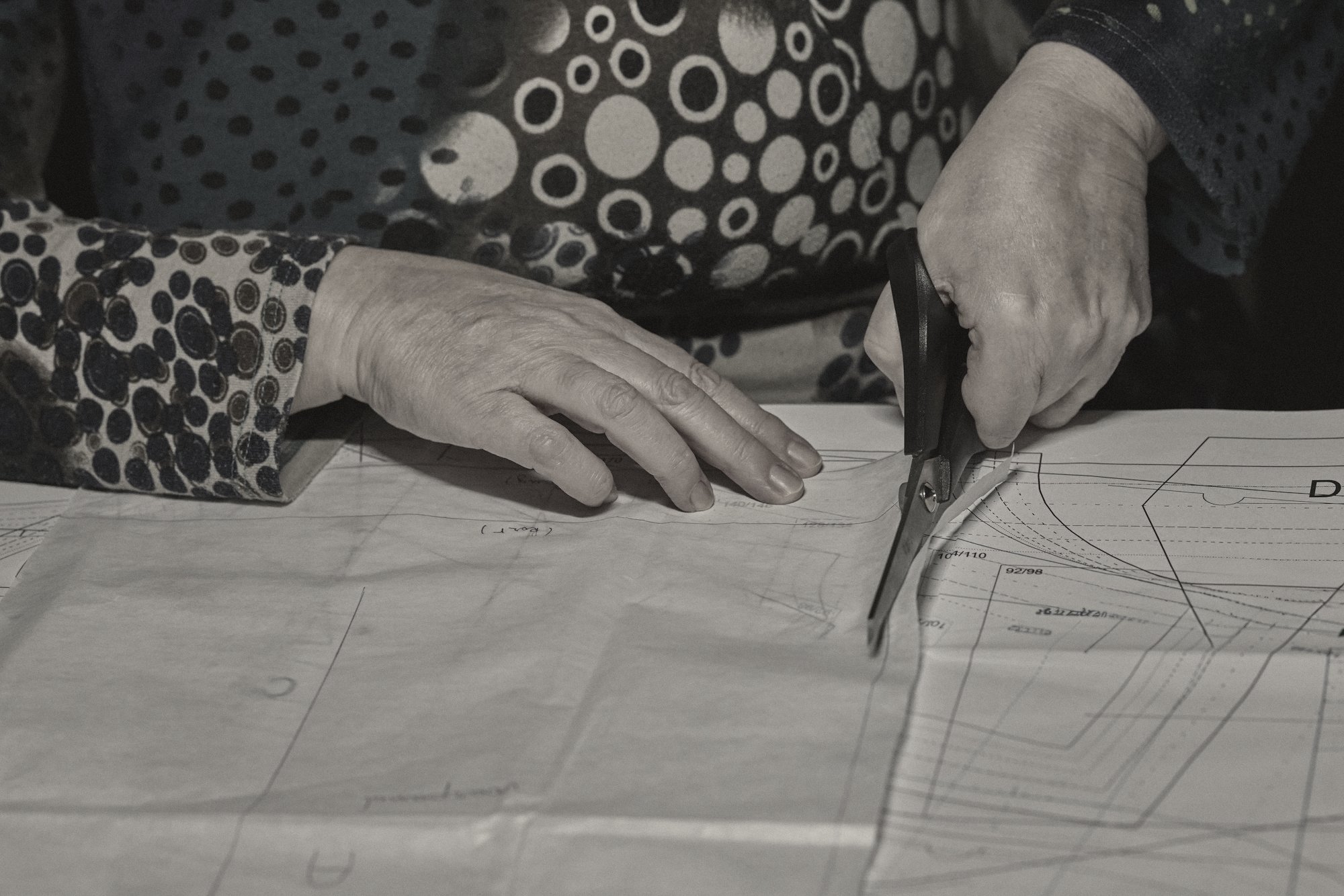A pattern cutter’s hands and scissors on a paper pattern