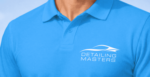 A photo of the Detailing Masters logo imprinted in white on the chest area of a brand blue polo shirt worn by a male model