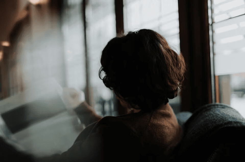 A person sitting by a window reading in a softly lit room, symbolizing what a LinkedIn impression means in a B2B guide for 2026.