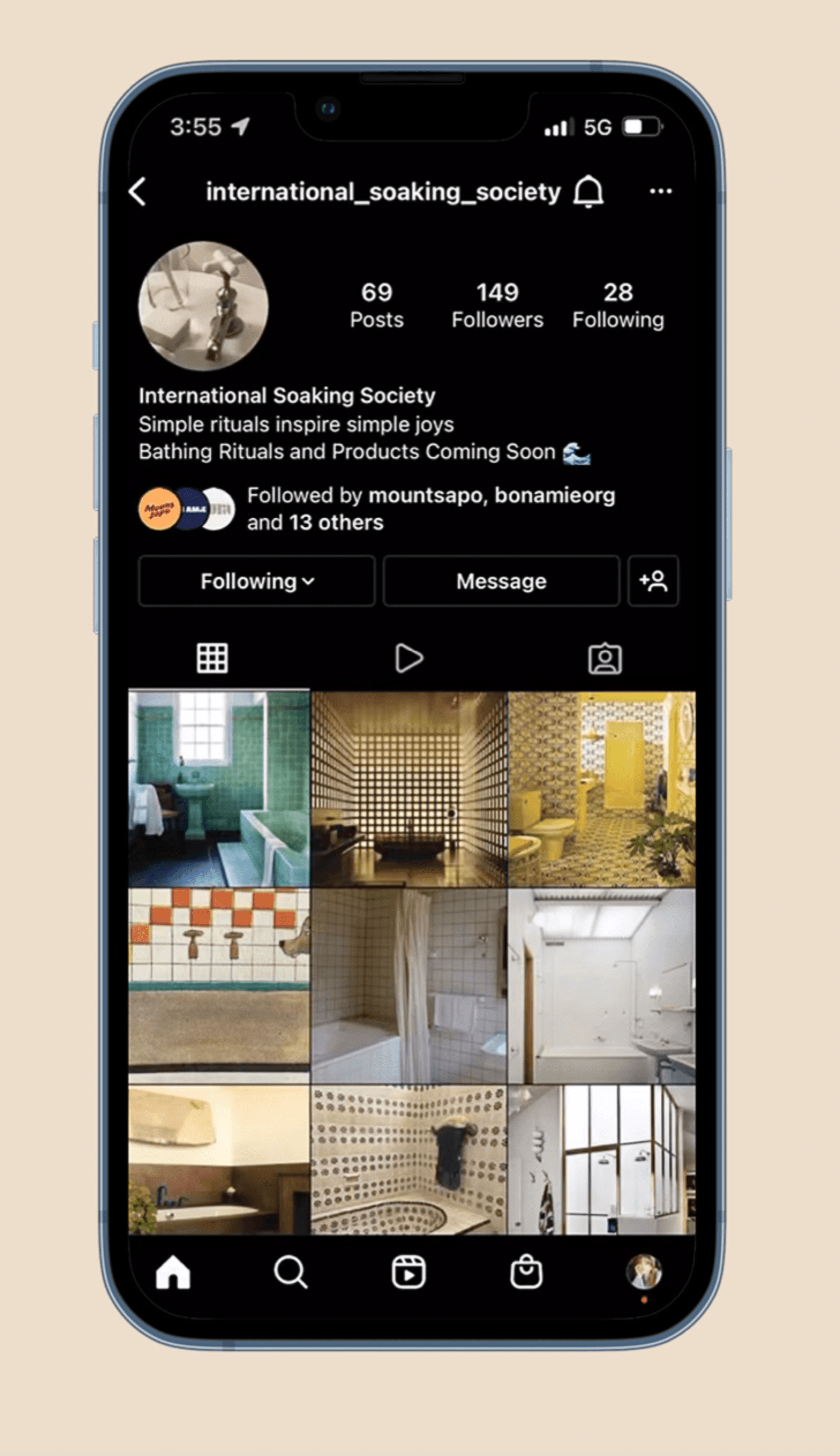 A smartphone displays a grid of thumbnails showcasing various bathroom and home design styles. The top bar shows the username “international_soaking_society,” 69 posts, 149 followers, and 28 following. The profile picture is a circular image with a bathroom sink. The screen includes navigation buttons for “Following” and “Message,” and a search icon. The thumbnails feature diverse design elements, including minimalist and modern styles.