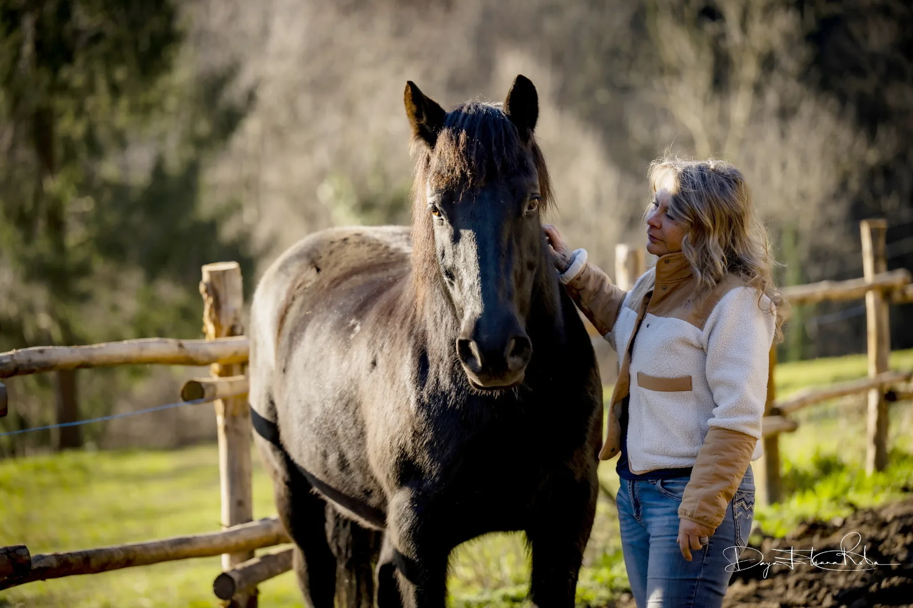 Daya accanto a un cavallo dal mantello scuro, con una mano appoggiata sul collo