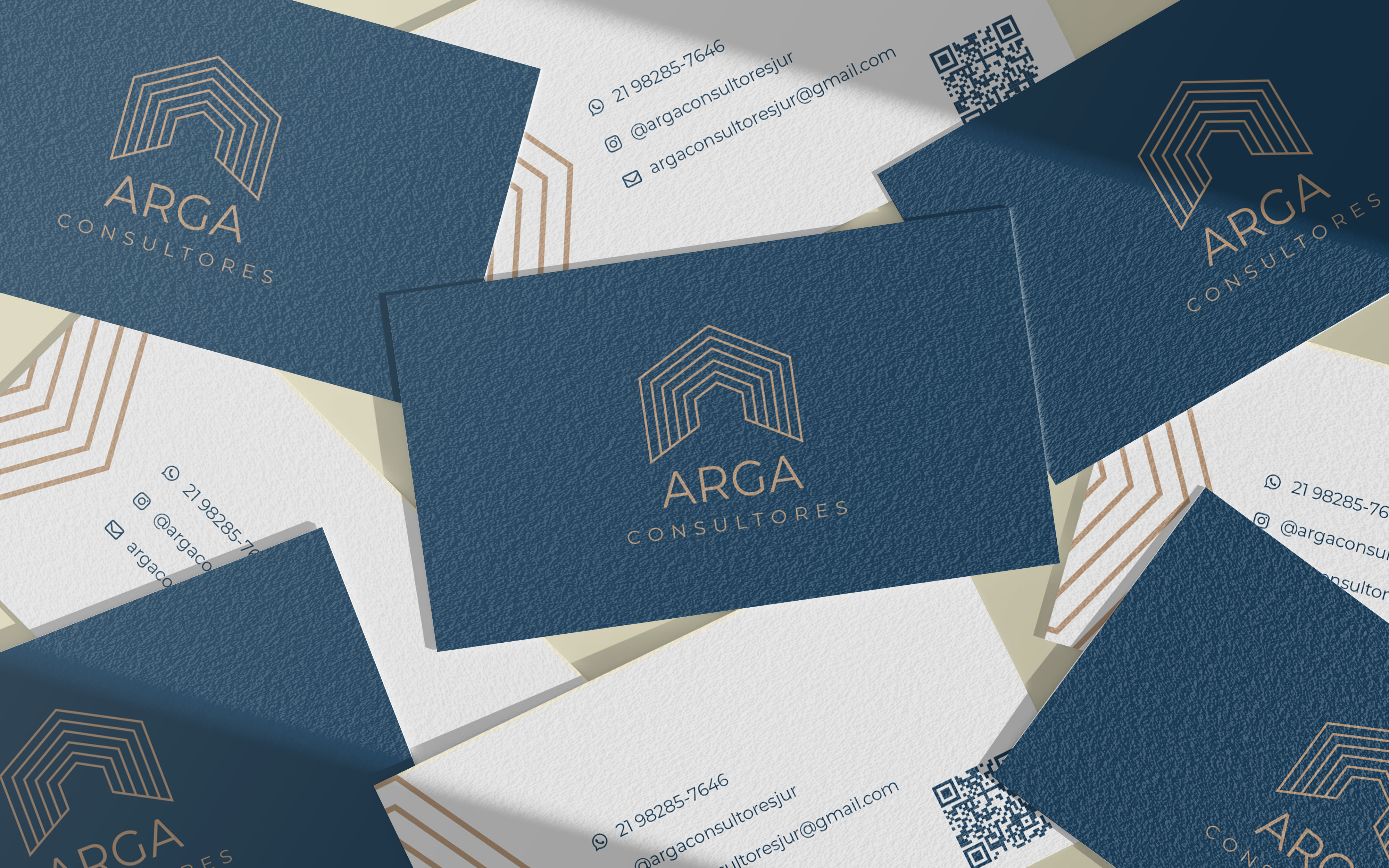 Cartões de visitas da Arga Consultores vistos de frente e verso espalhados em uma mesa