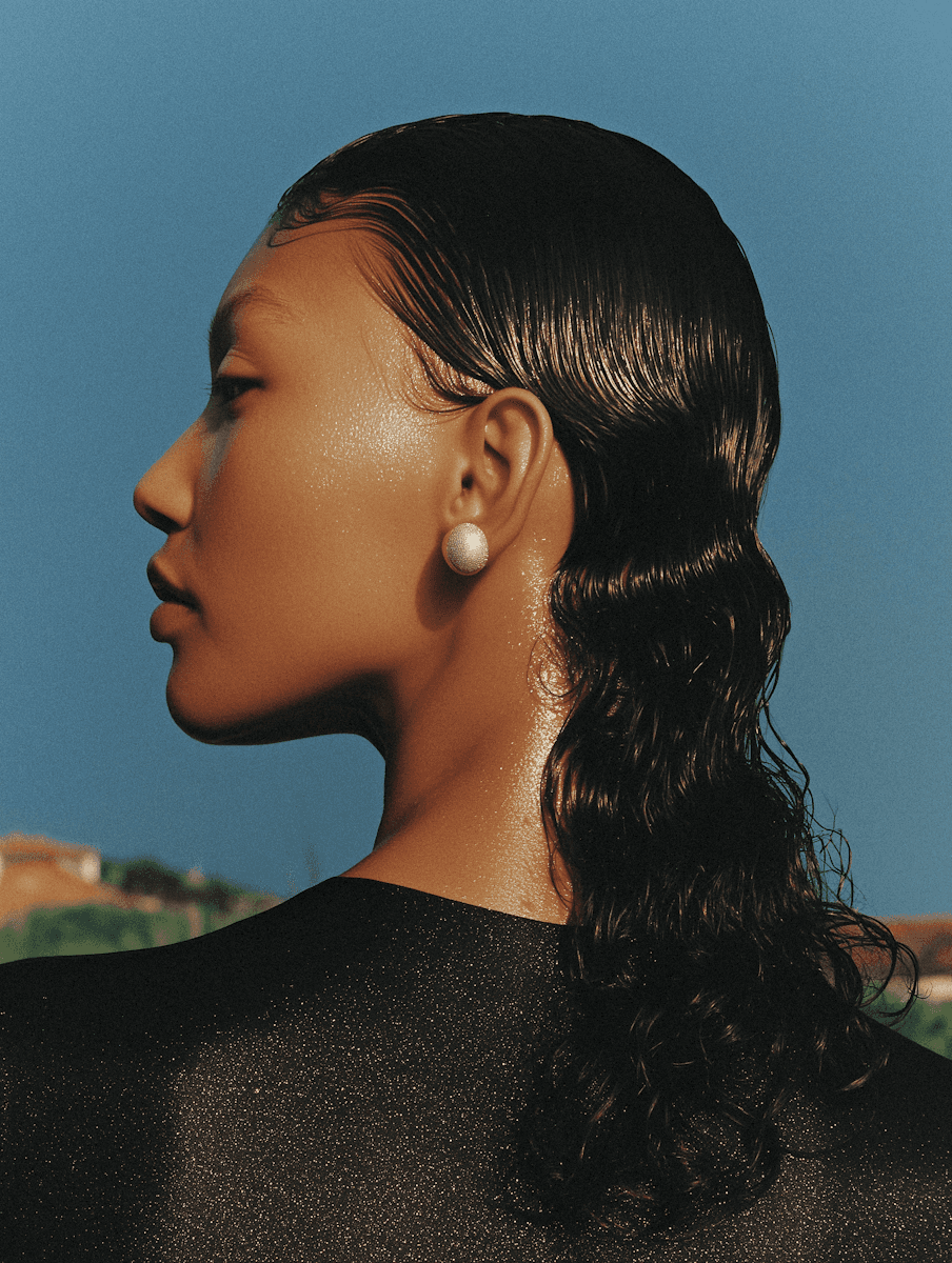 Side profile portrait of a woman wearing pearl earrings.