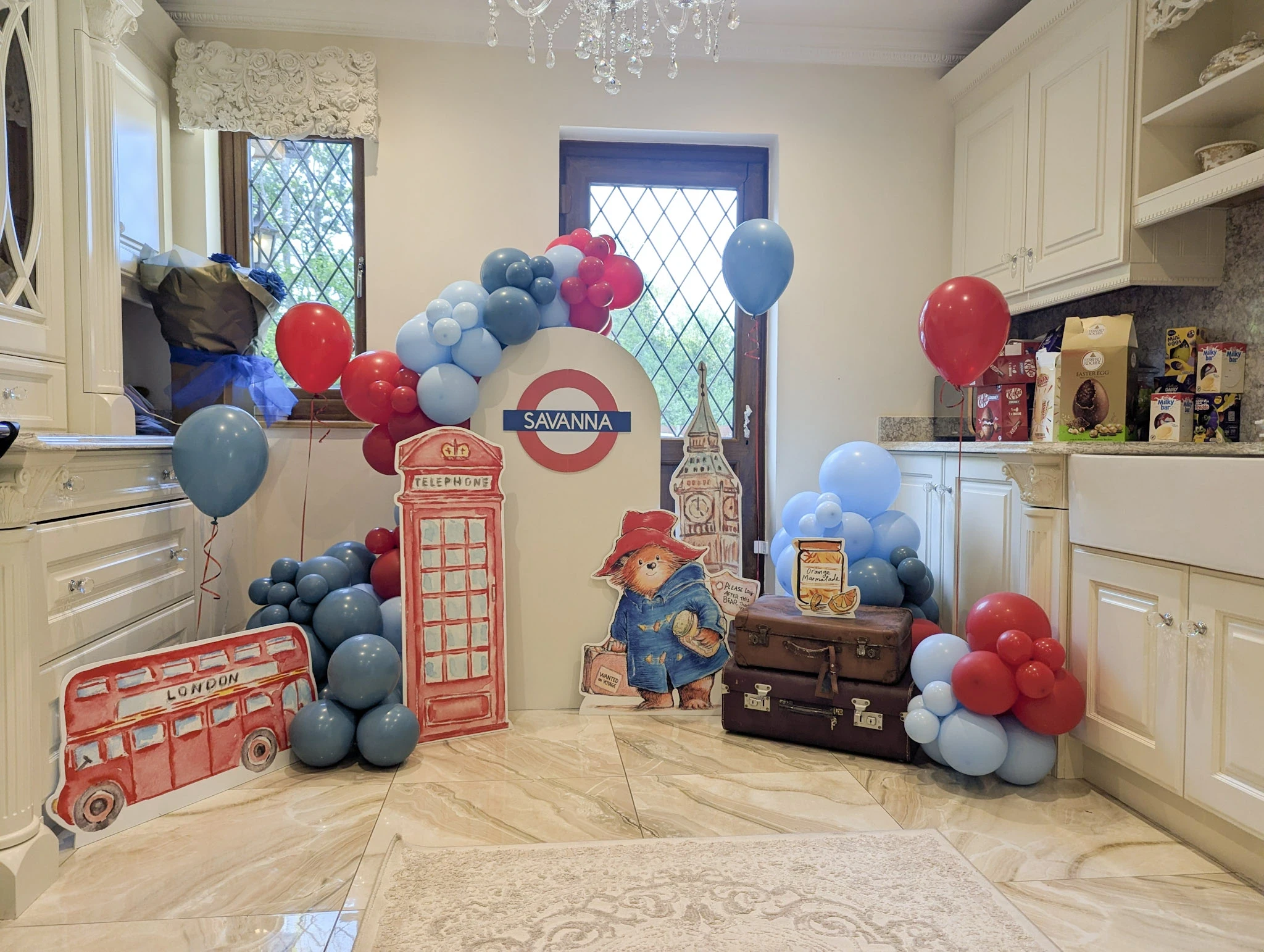 London-themed balloon display with Underground sign, Paddington Bear, and red and blue garlands in a kitchen