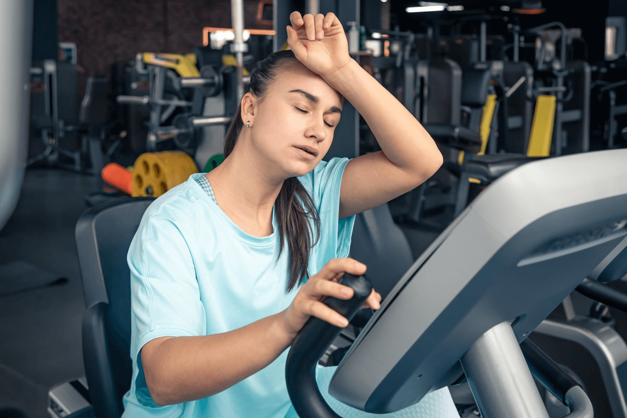 Woman experiencing muscle fatigue while doing a workout at the gym.