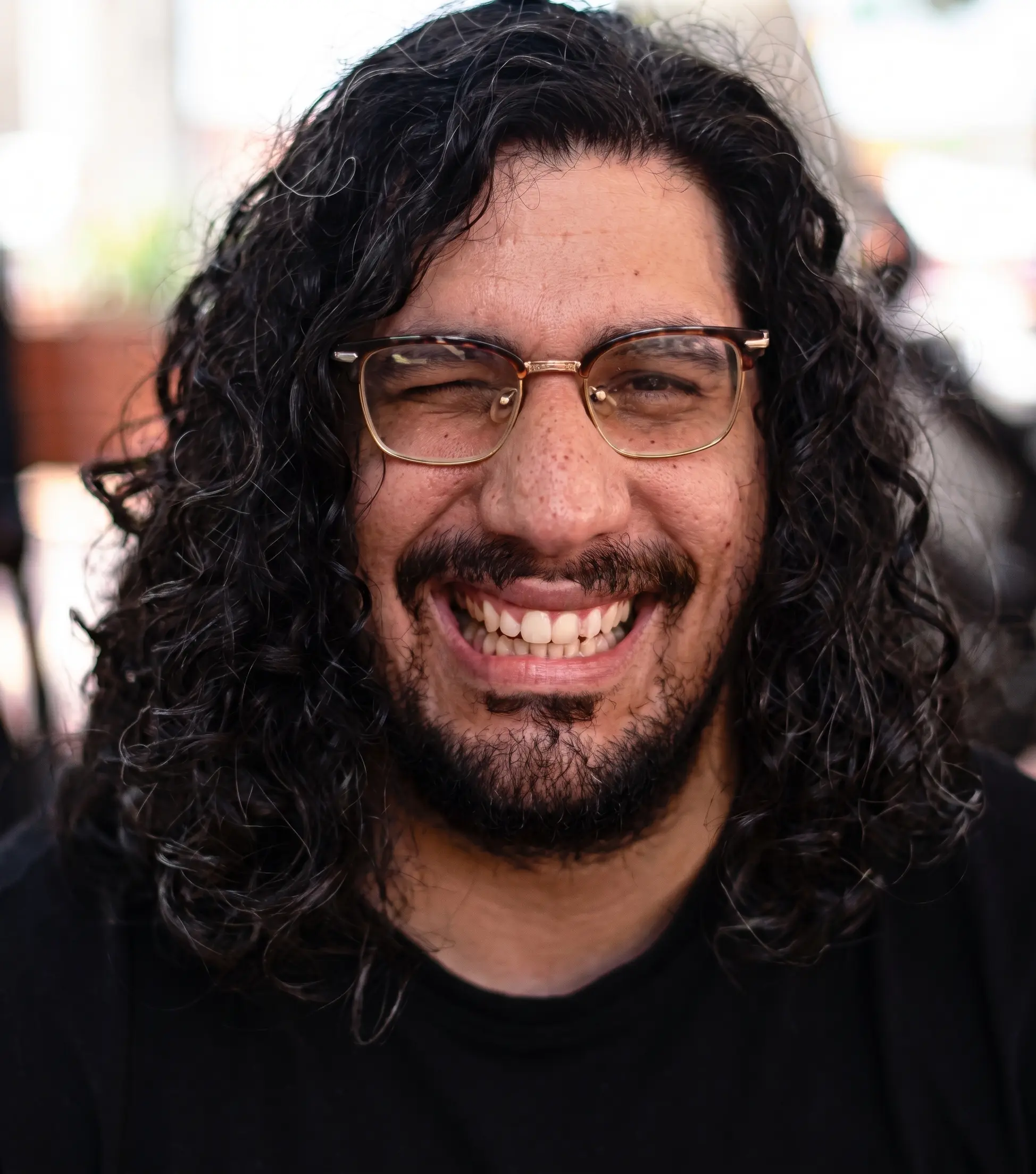 A thoughtful young person with dark hair gazes to the side, captured in soft black and white lighting.